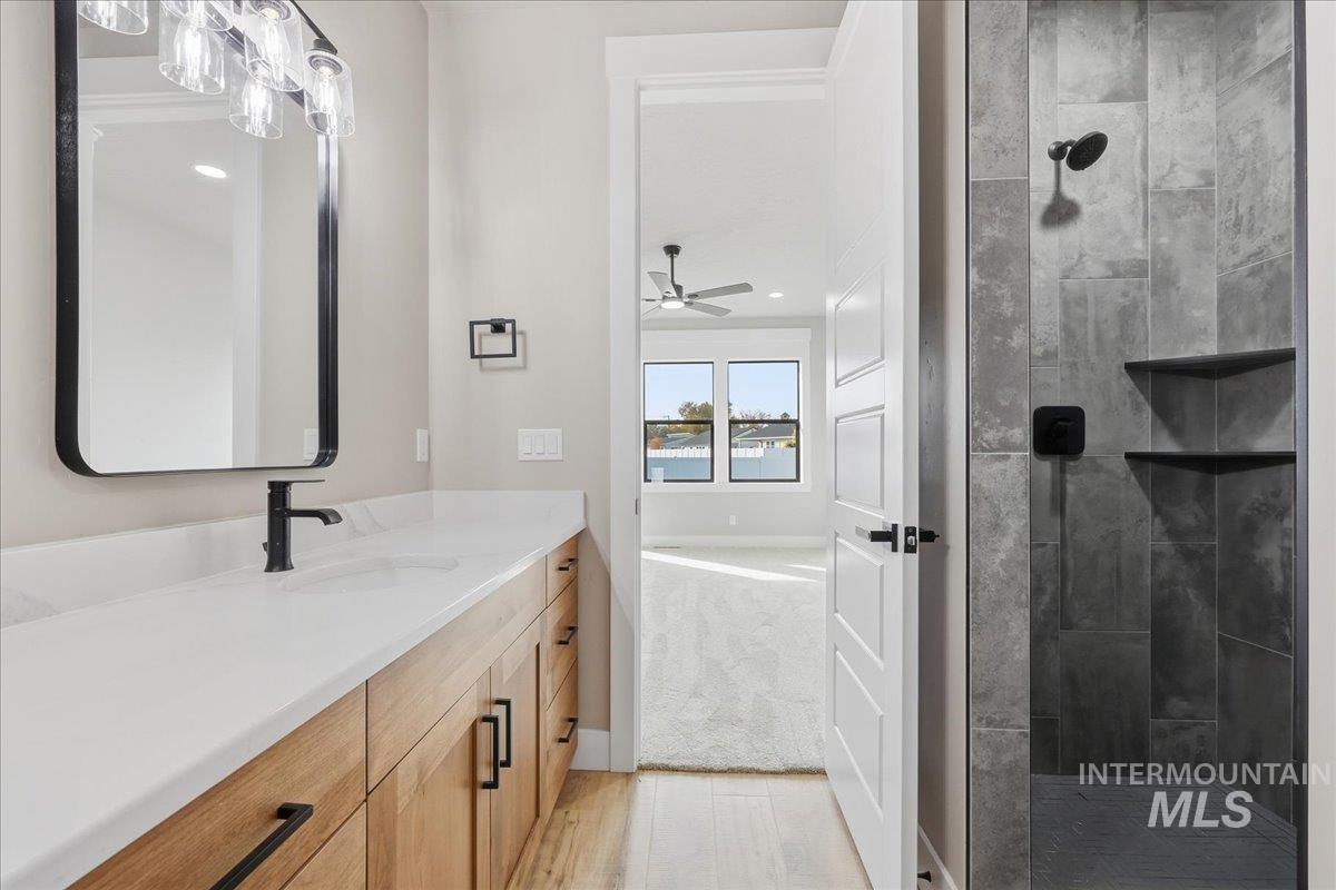 Full bath with vanity, a stall shower, ceiling fan, and light carpet