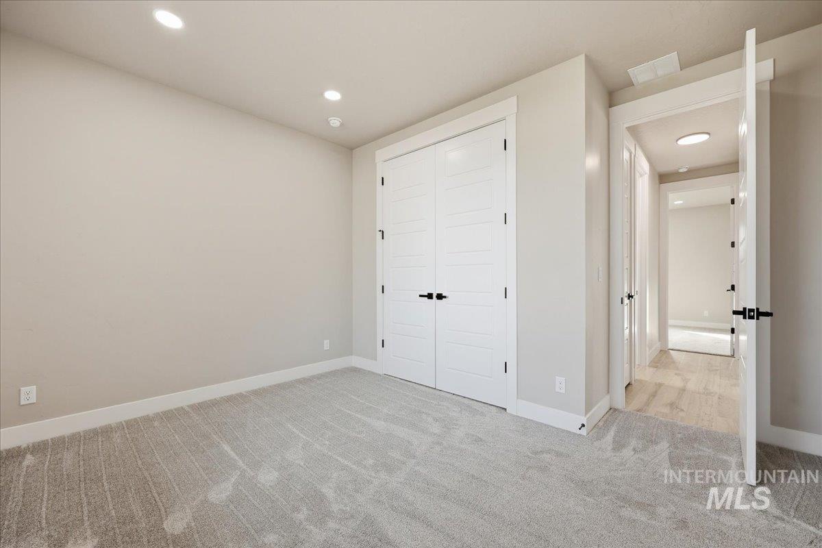 Unfurnished bedroom with recessed lighting, light colored carpet, and a closet