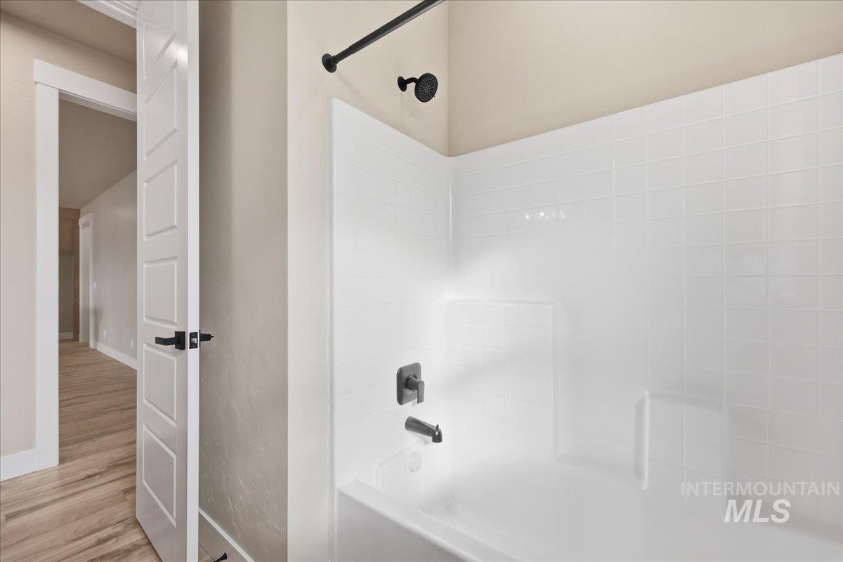 Full bath with bathing tub / shower combination and wood finished floors