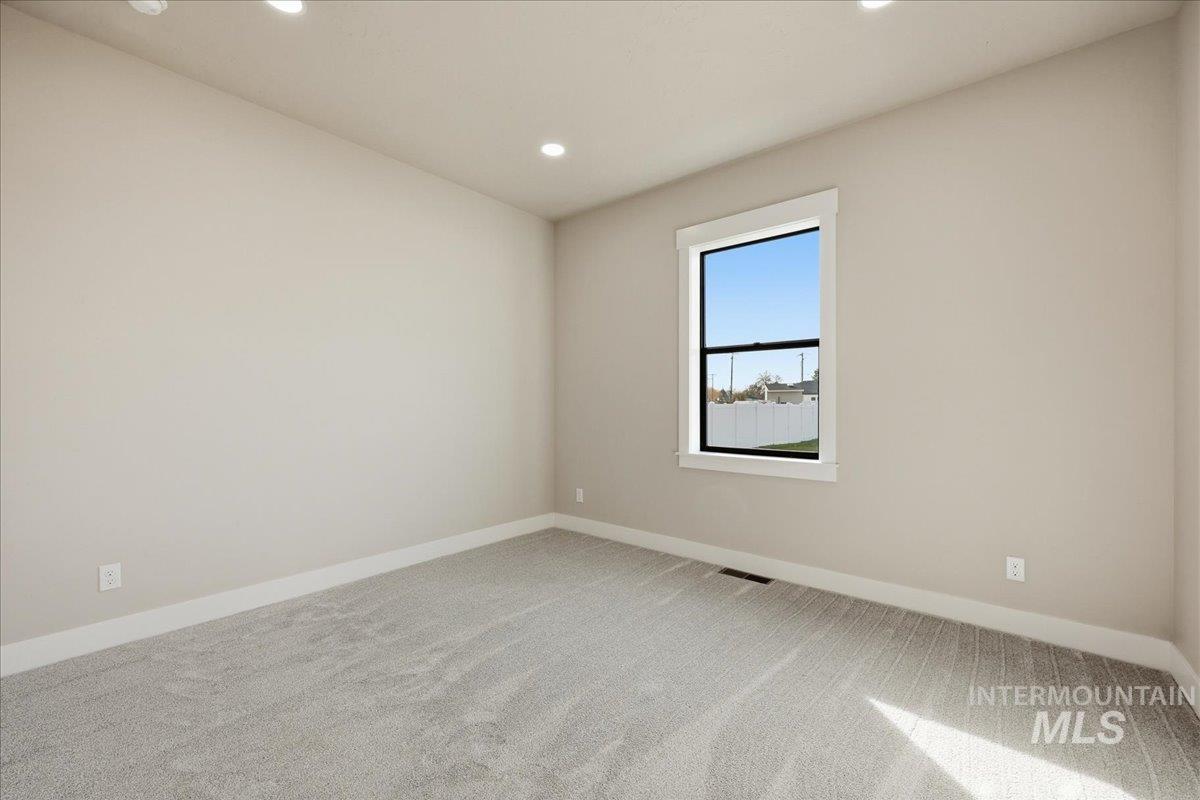 Empty room with light carpet and recessed lighting