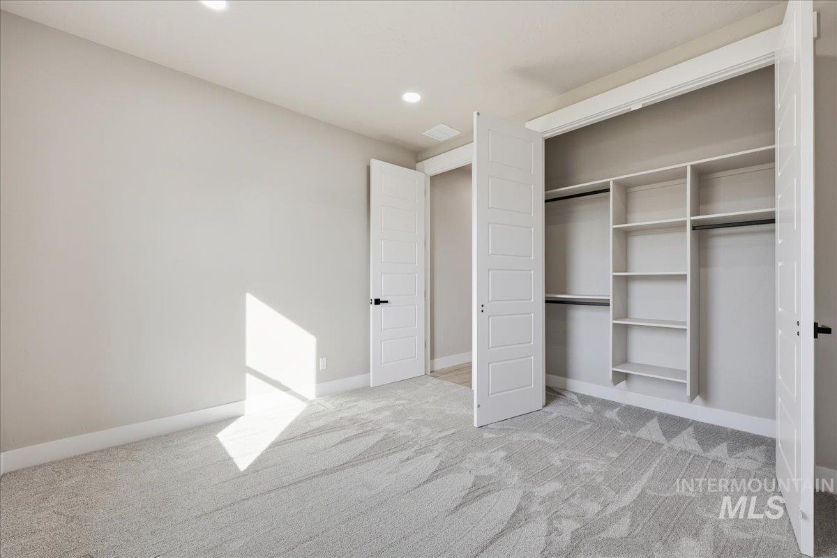 Unfurnished bedroom featuring light carpet, recessed lighting, and a closet