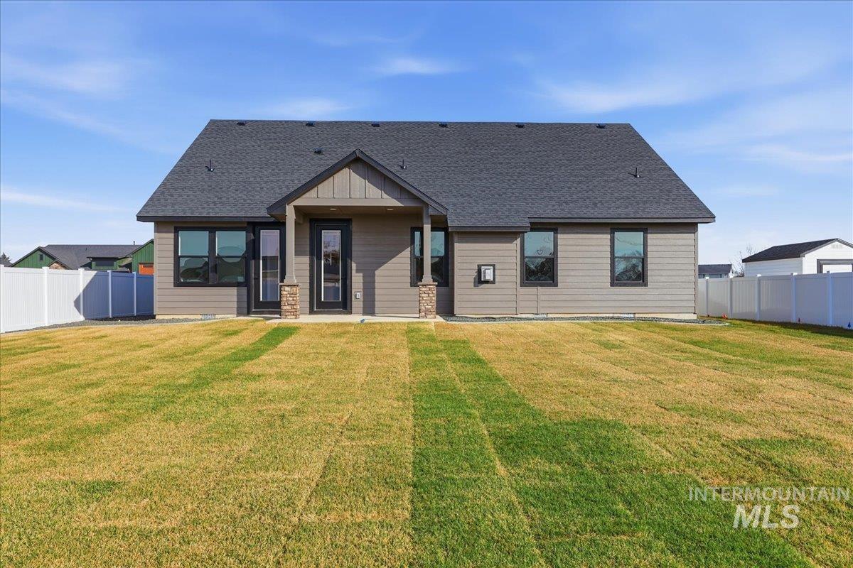 Rear view of property featuring a fenced backyard, roof with shingles, and a patio area