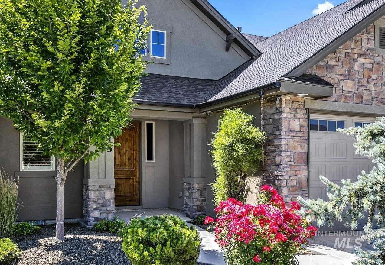 Doorway to property featuring stone siding, a shingled roof, and a garage