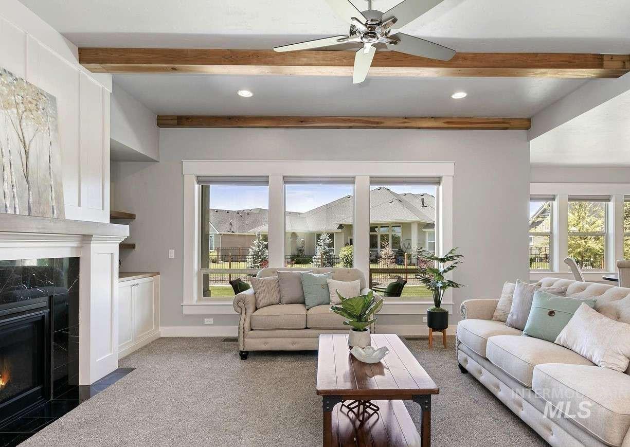 Living room featuring beam ceiling, carpet flooring, a high end fireplace, ceiling fan, and recessed lighting
