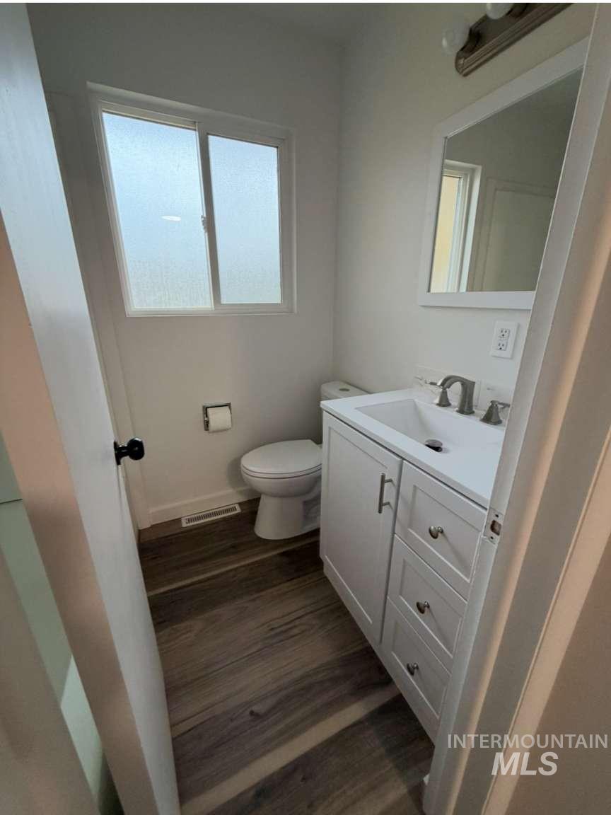 Half bathroom with vanity and dark wood-type flooring