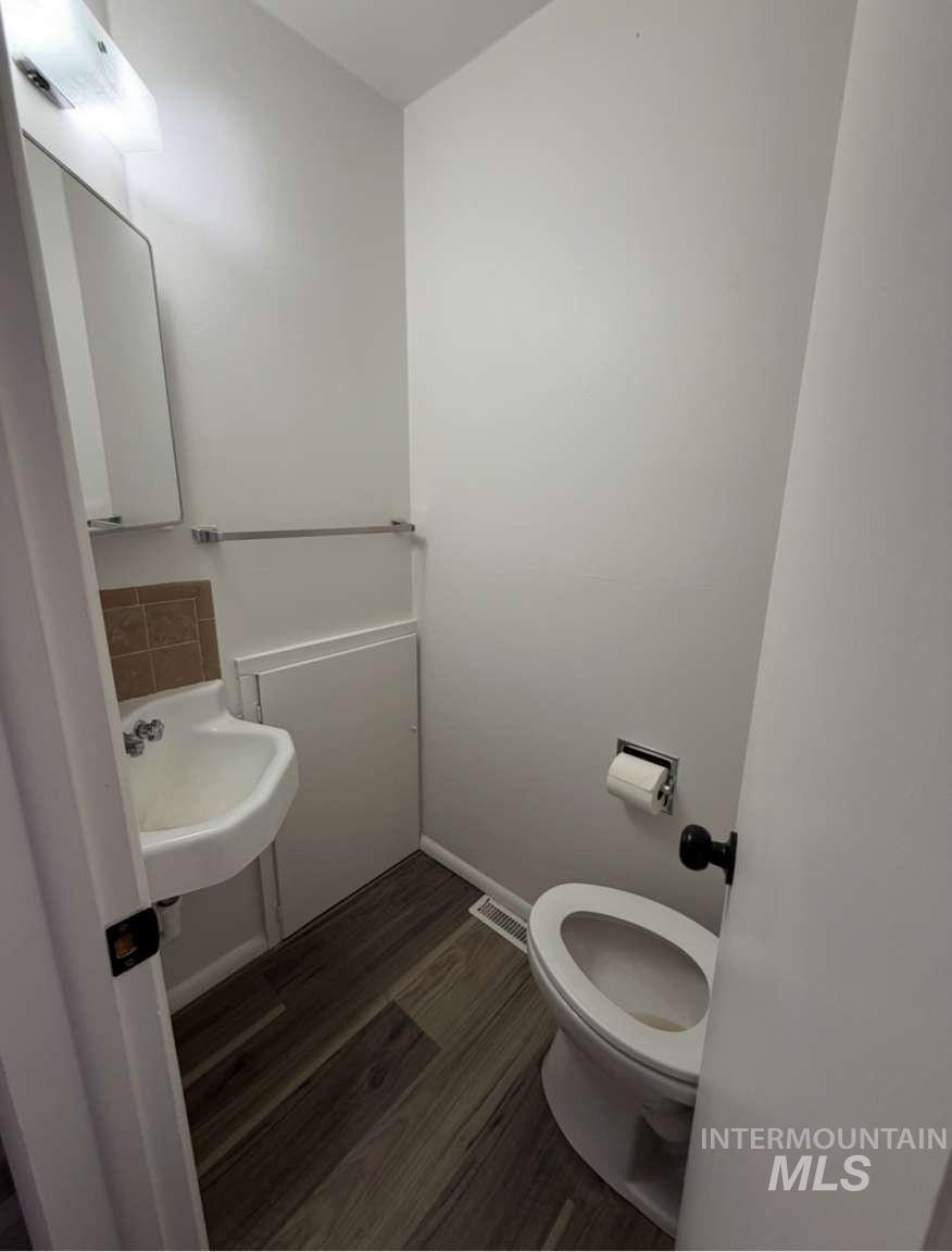 Half bath featuring dark wood finished floors and toilet