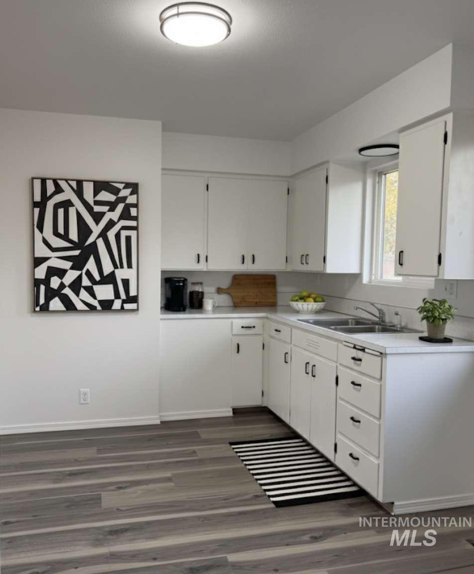 Kitchen featuring light countertops, dark wood-style floors, and white cabinets
