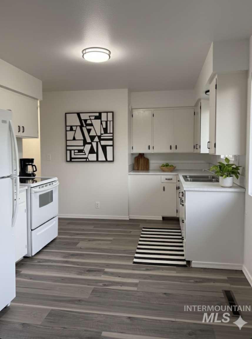 Kitchen featuring light countertops, white appliances, white cabinets, and dark wood-type flooring