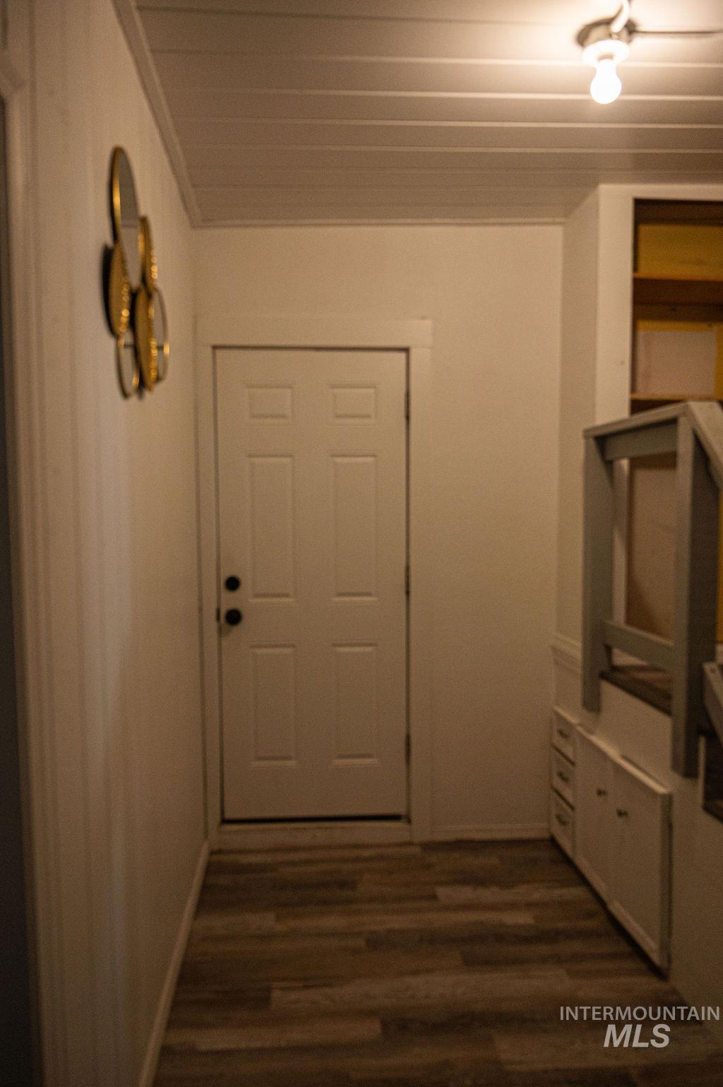 Back entrance with hall featuring dark wood finished floors and baseboards with storage.