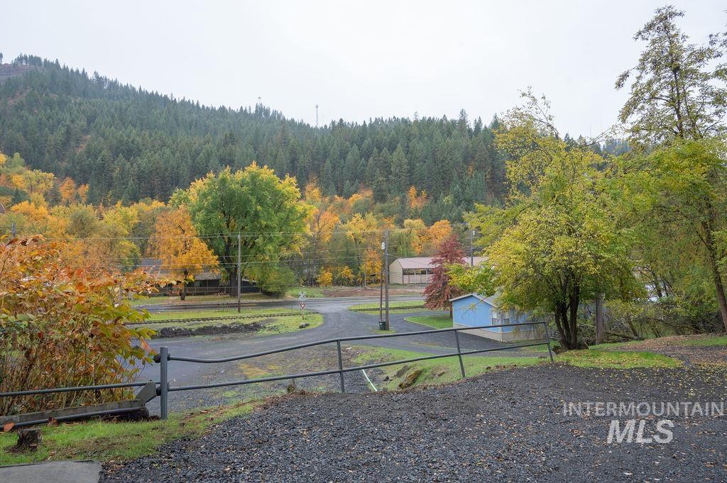View of dirt / gravel road with a gated entry and a view of trees