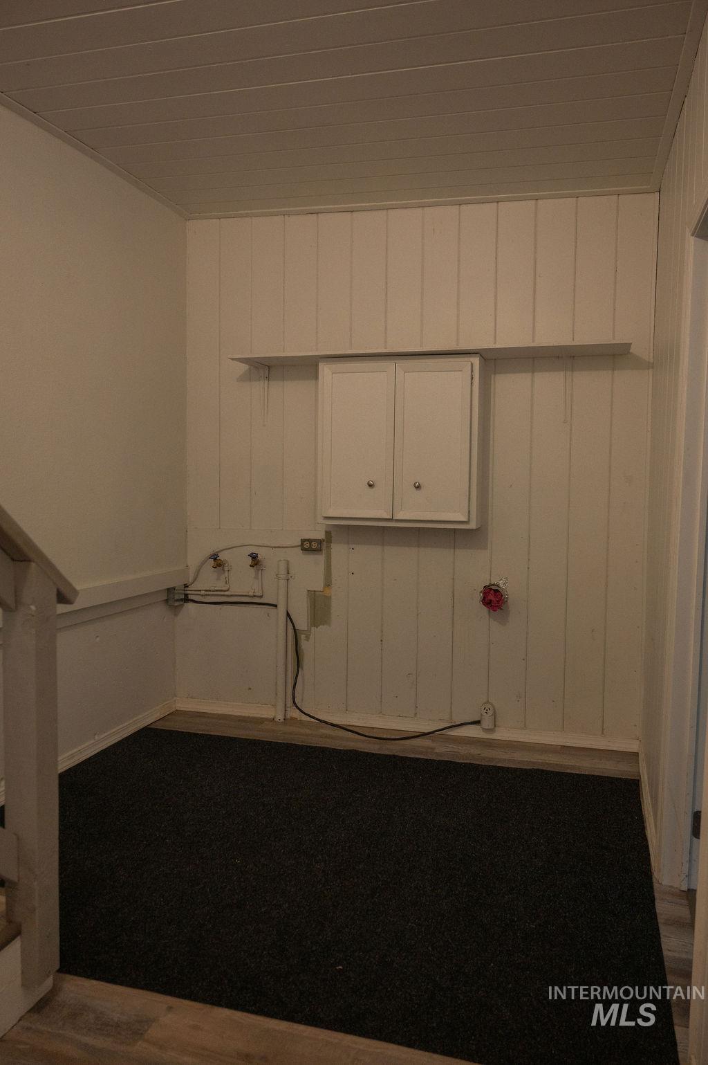 Laundry area featuring dark wood-style floors, wood walls, and hookup for a washing machine