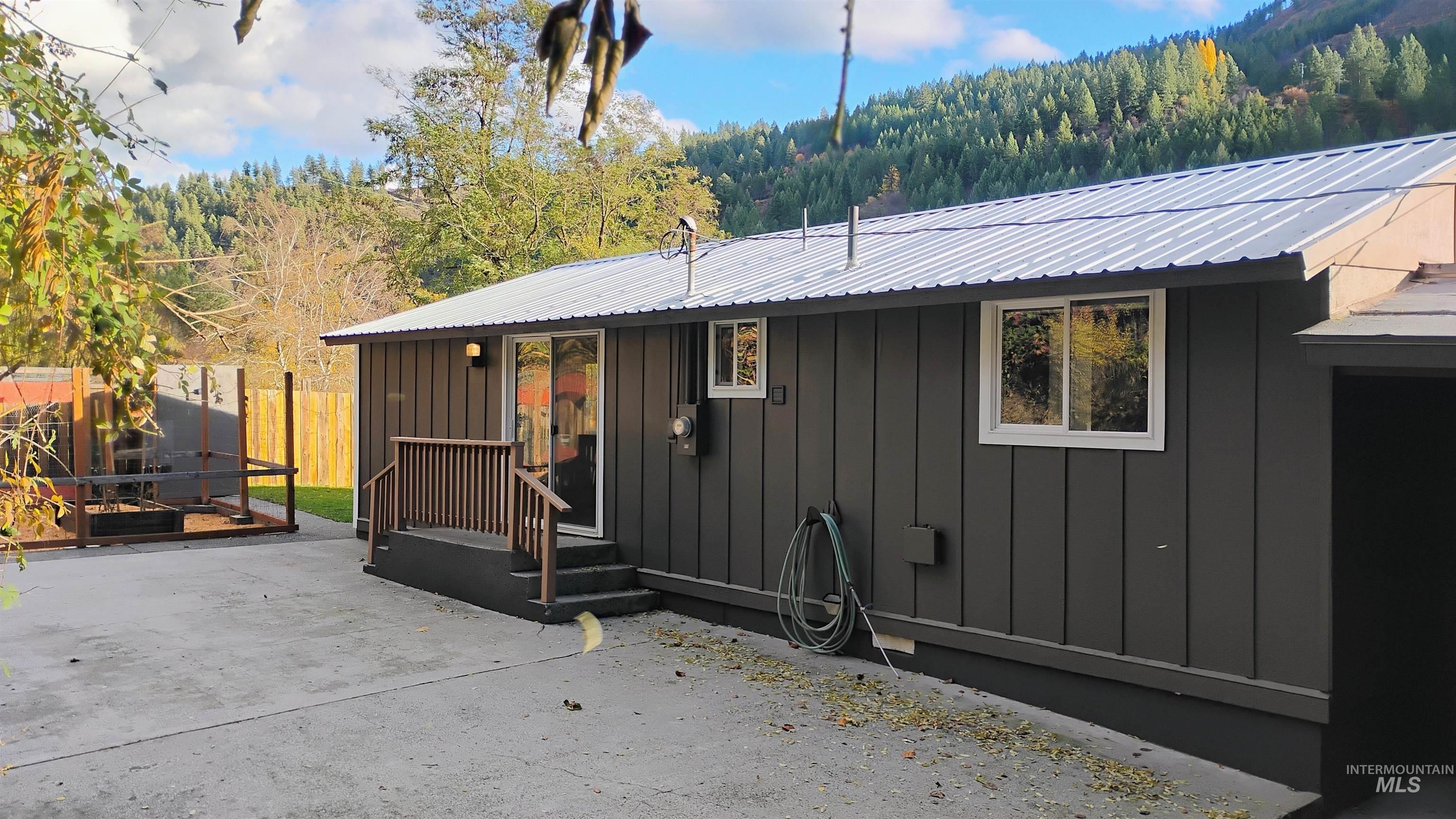 Rear view of property with board and batten siding and a metal roof