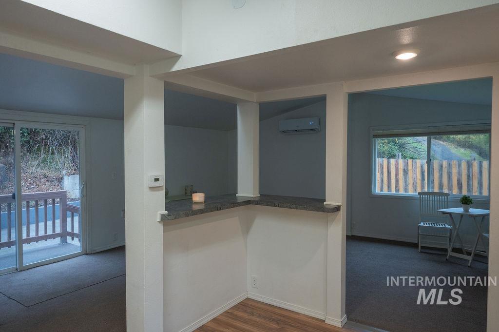 Kitchen featuring dark colored carpet, dark wood-type flooring, and a wall unit AC
