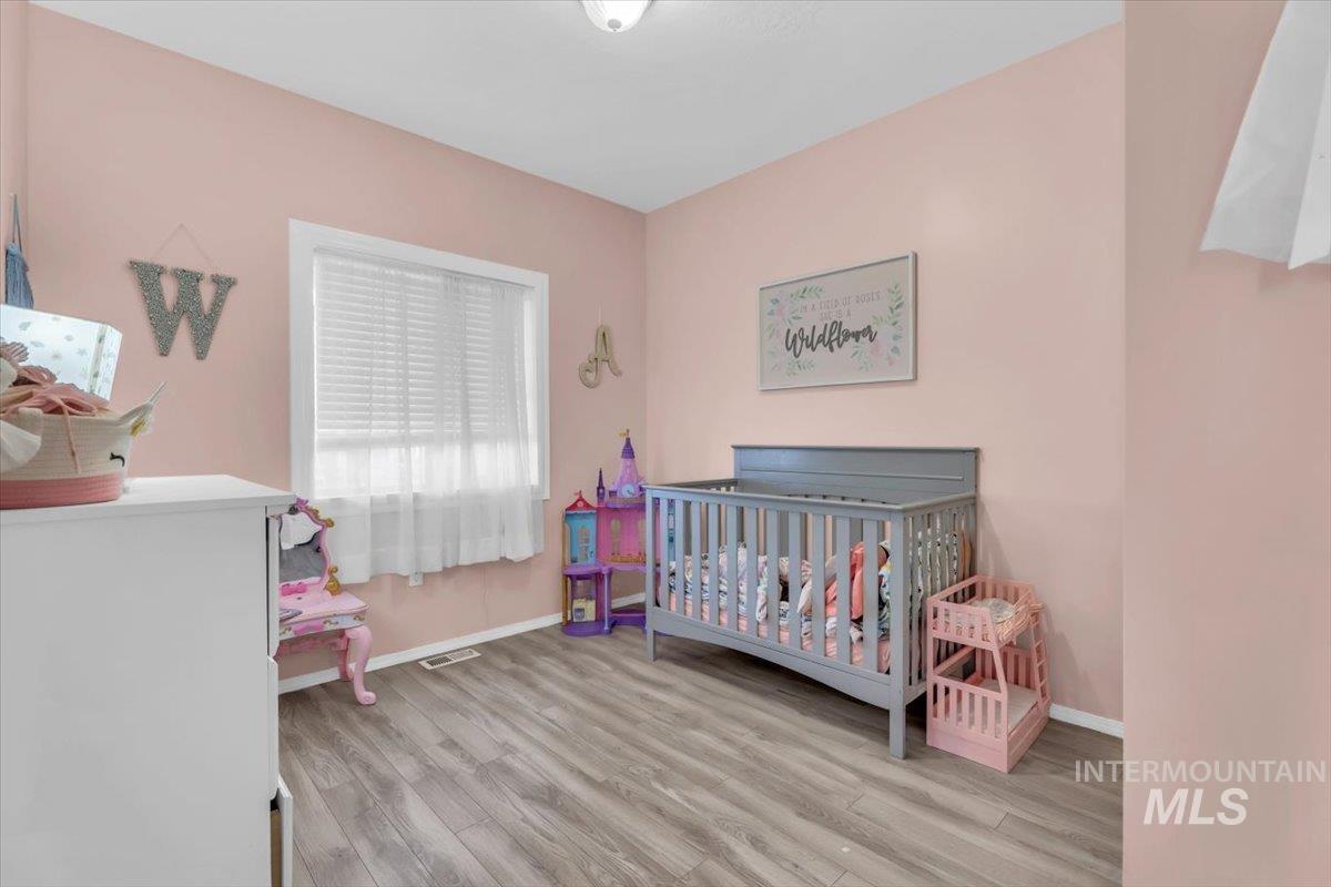 Bedroom featuring a crib and light wood-type flooring