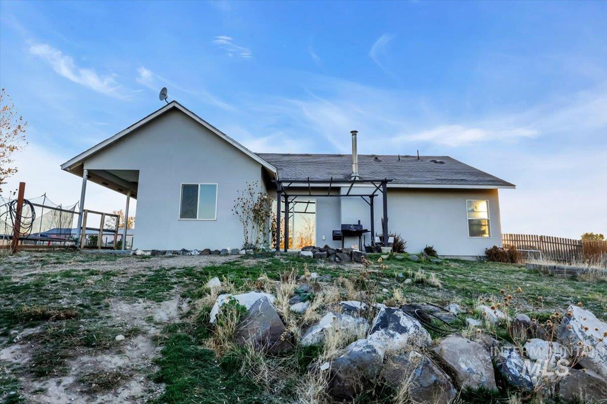 Rear view of property featuring stucco siding, a patio area, roof with shingles, and a pergola