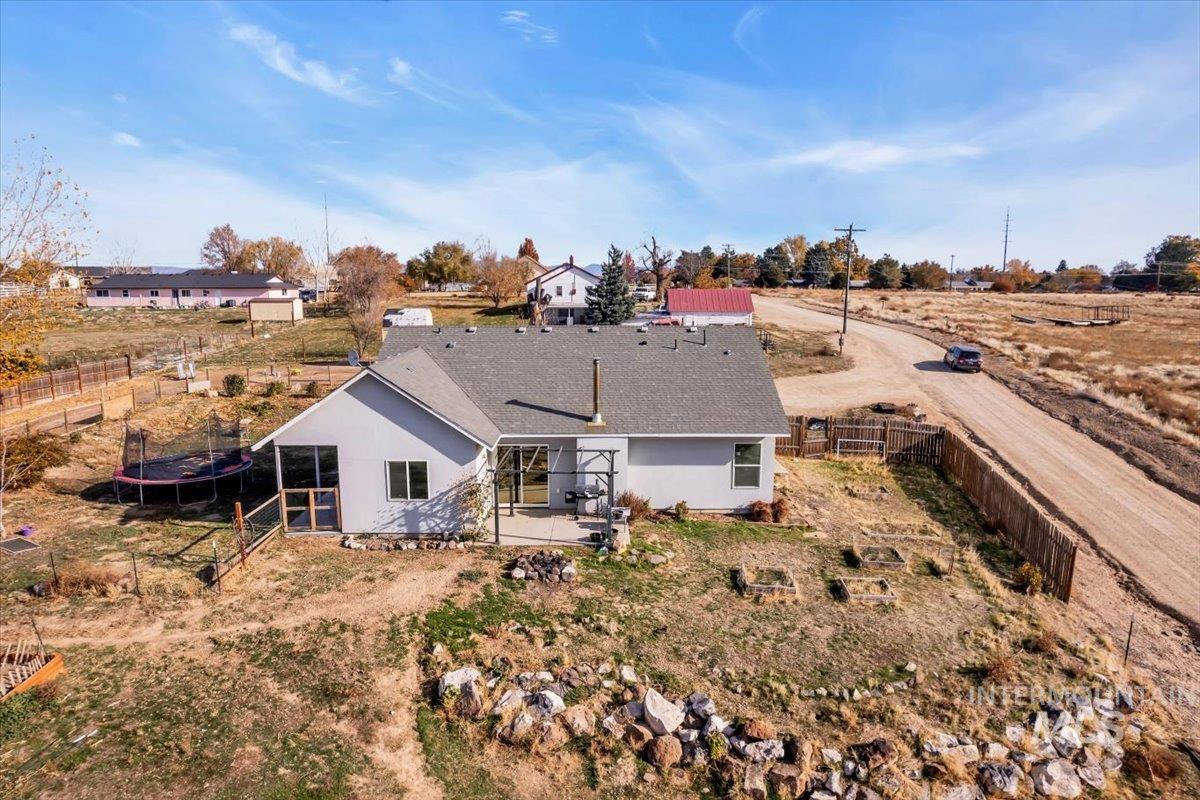 Rear view of property with a trampoline, a fenced backyard, and stucco siding