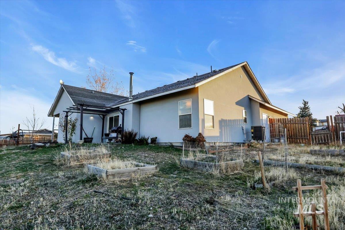 Rear view of house with a vegetable garden, stucco siding, and a patio area