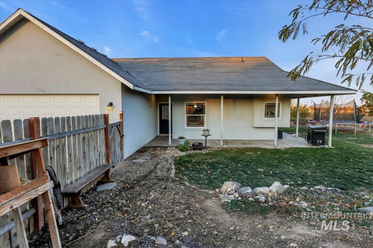 View of front of home with a trampoline, stucco siding, roof with shingles, and a patio