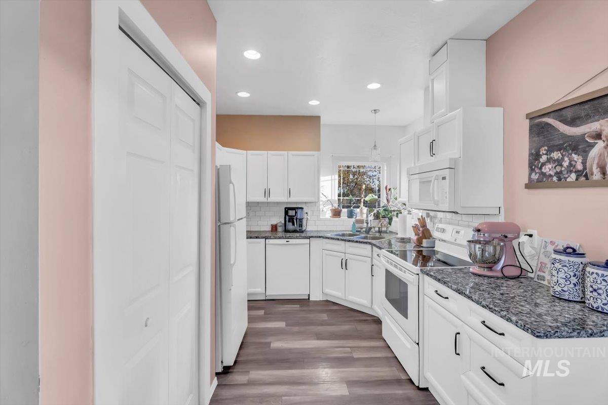 Kitchen with white appliances, white cabinetry, dark wood-style flooring, pendant lighting, and recessed lighting
