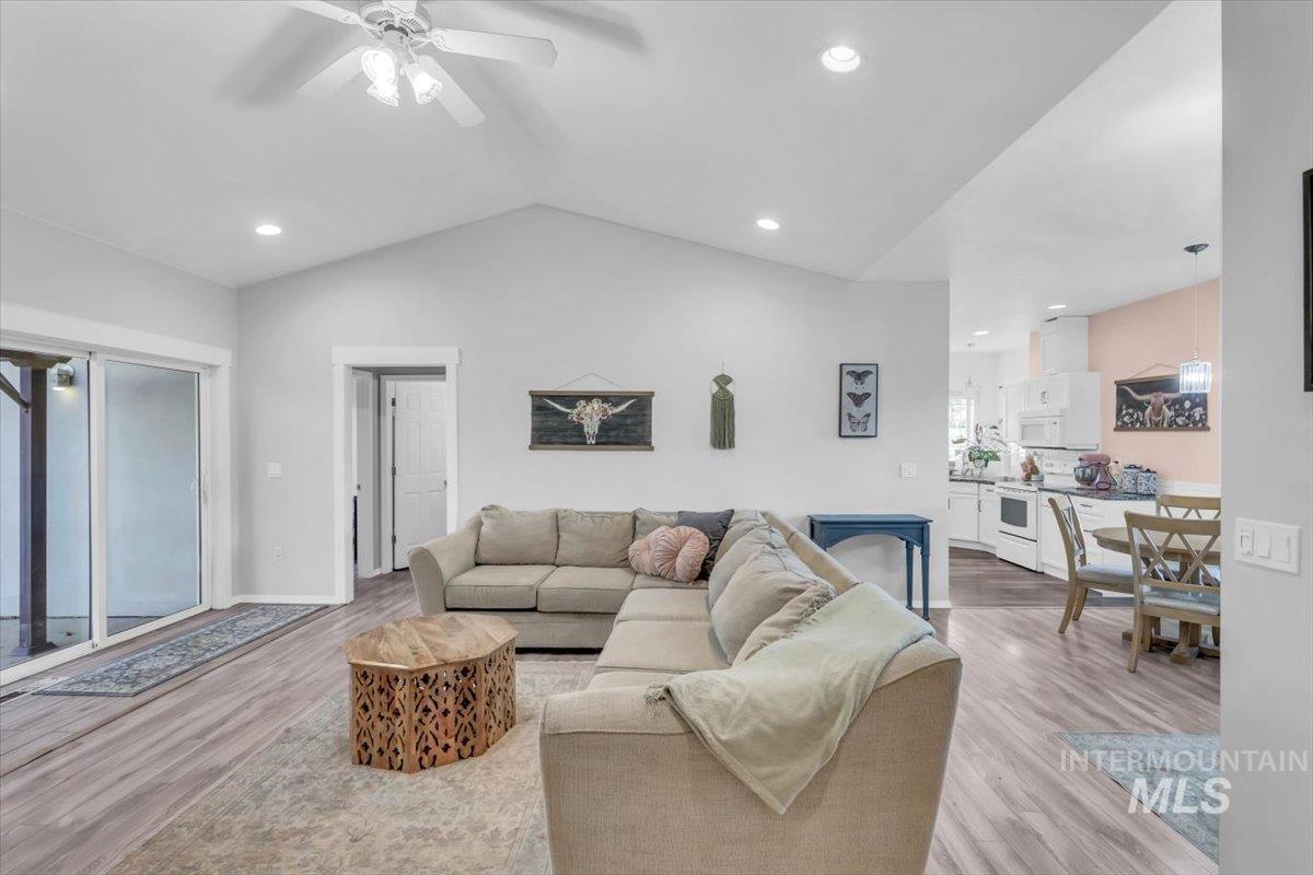 Living room featuring vaulted ceiling, light wood finished floors, recessed lighting, and a ceiling fan
