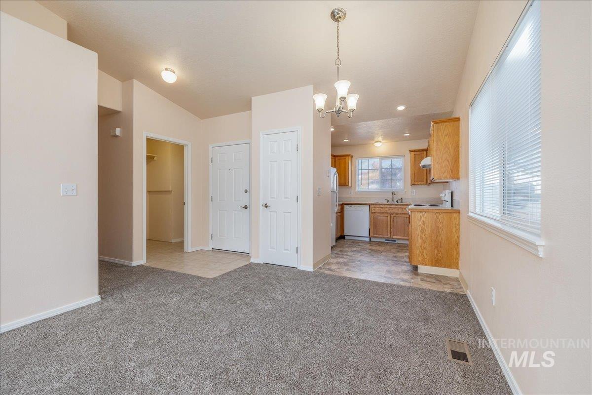 Kitchen with light colored carpet, pendant lighting, a chandelier, and white appliances