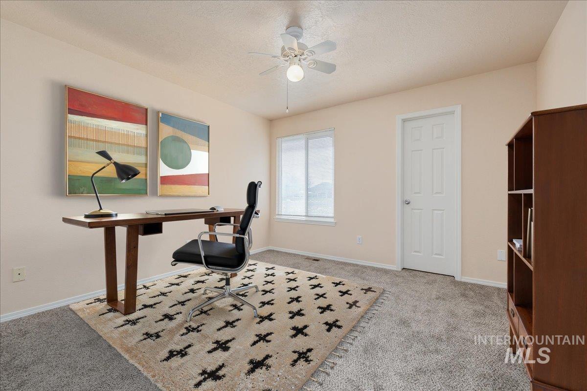 Office area with a textured ceiling, a ceiling fan, and light colored carpet