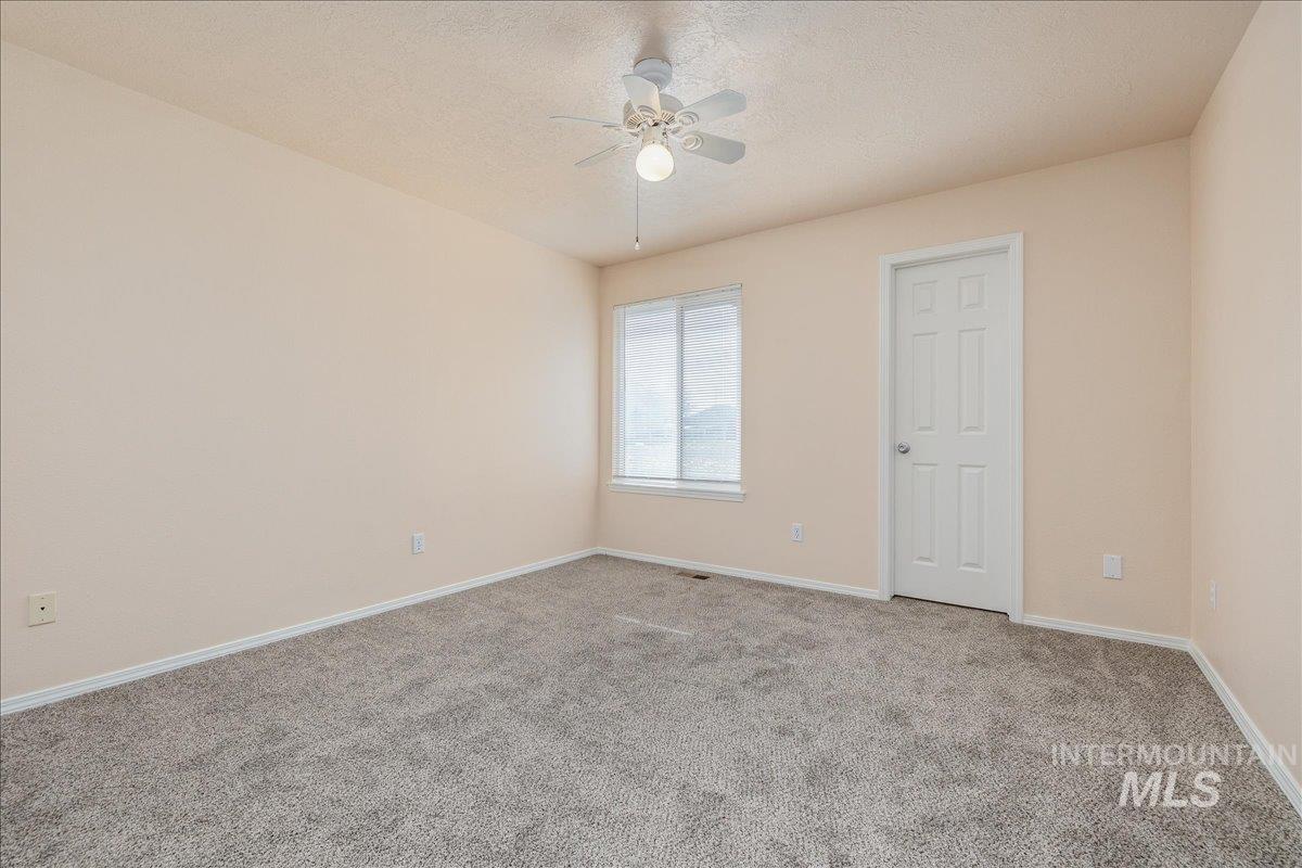 Carpeted spare room with a textured ceiling and a ceiling fan