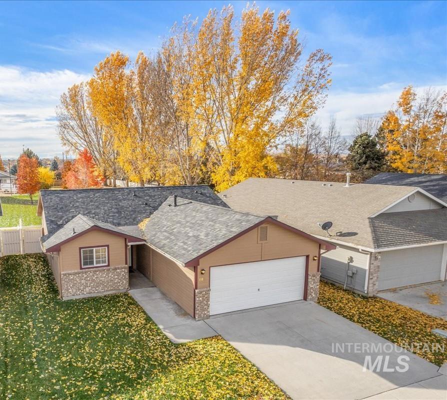Ranch-style home with driveway, roof with shingles, a garage, and brick siding