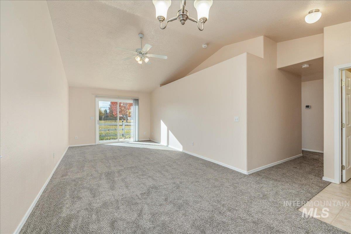 Spare room featuring carpet floors, a chandelier, vaulted ceiling, a textured ceiling, and ceiling fan