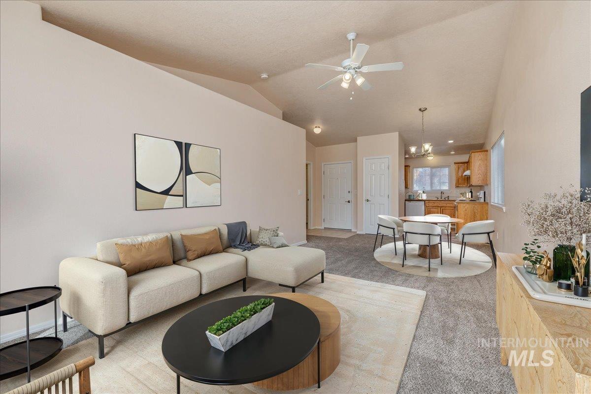 Living area with light carpet, lofted ceiling, a chandelier, and a ceiling fan