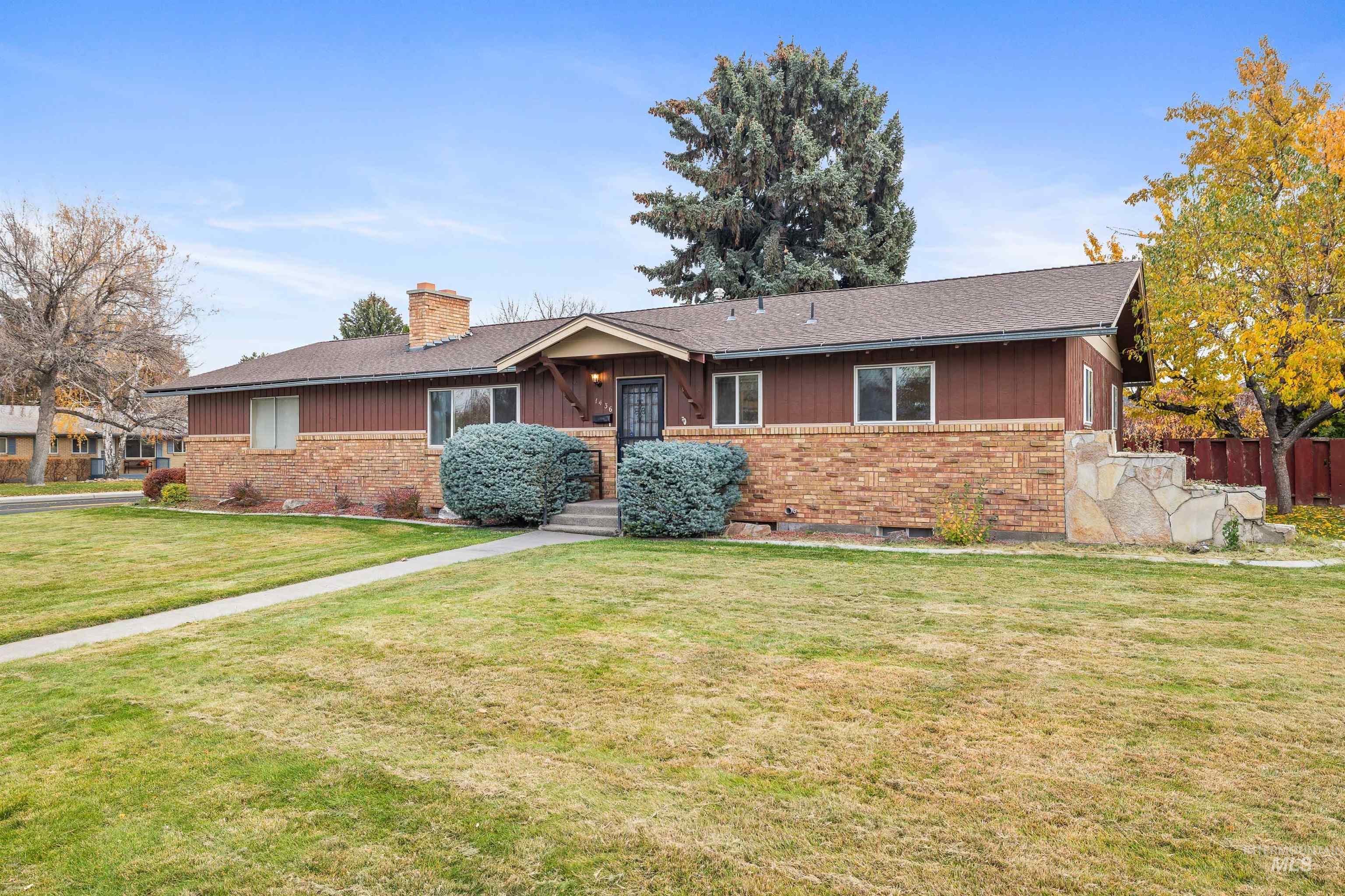 Ranch-style home featuring brick siding, a chimney, and roof with shingles