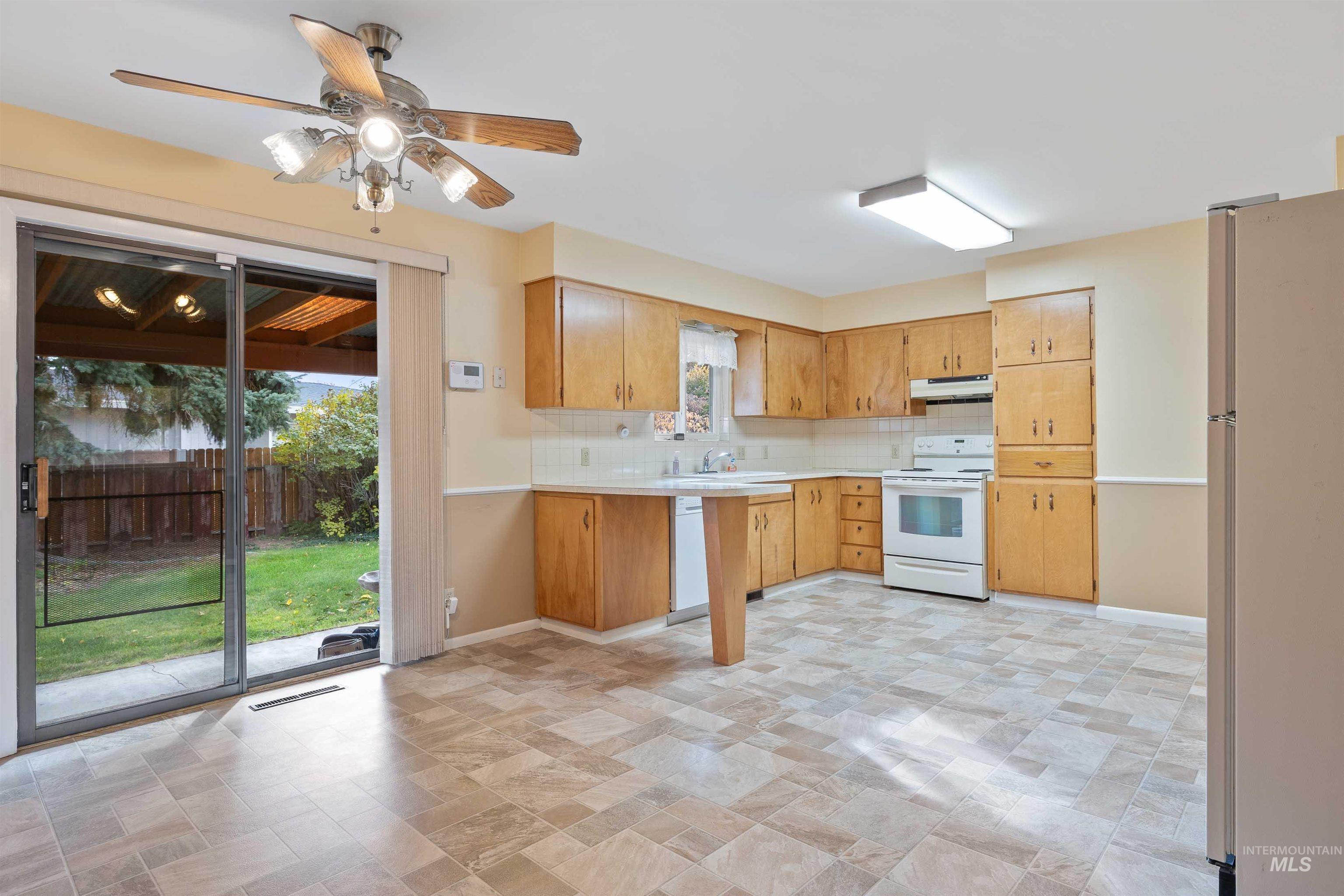 Kitchen featuring tasteful backsplash, white appliances, light countertops, a peninsula, and a ceiling fan
