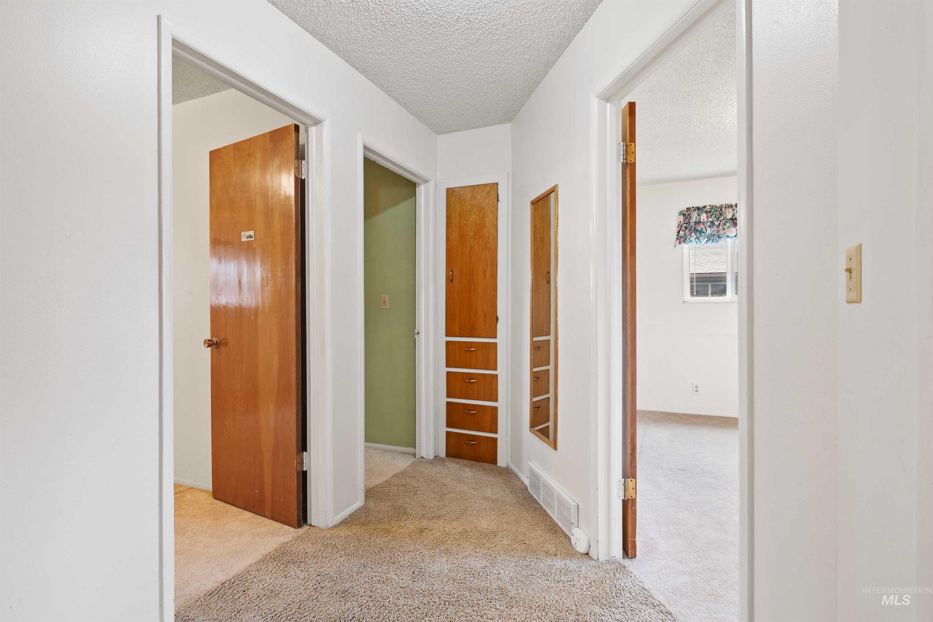 Hallway with a textured ceiling and light carpet