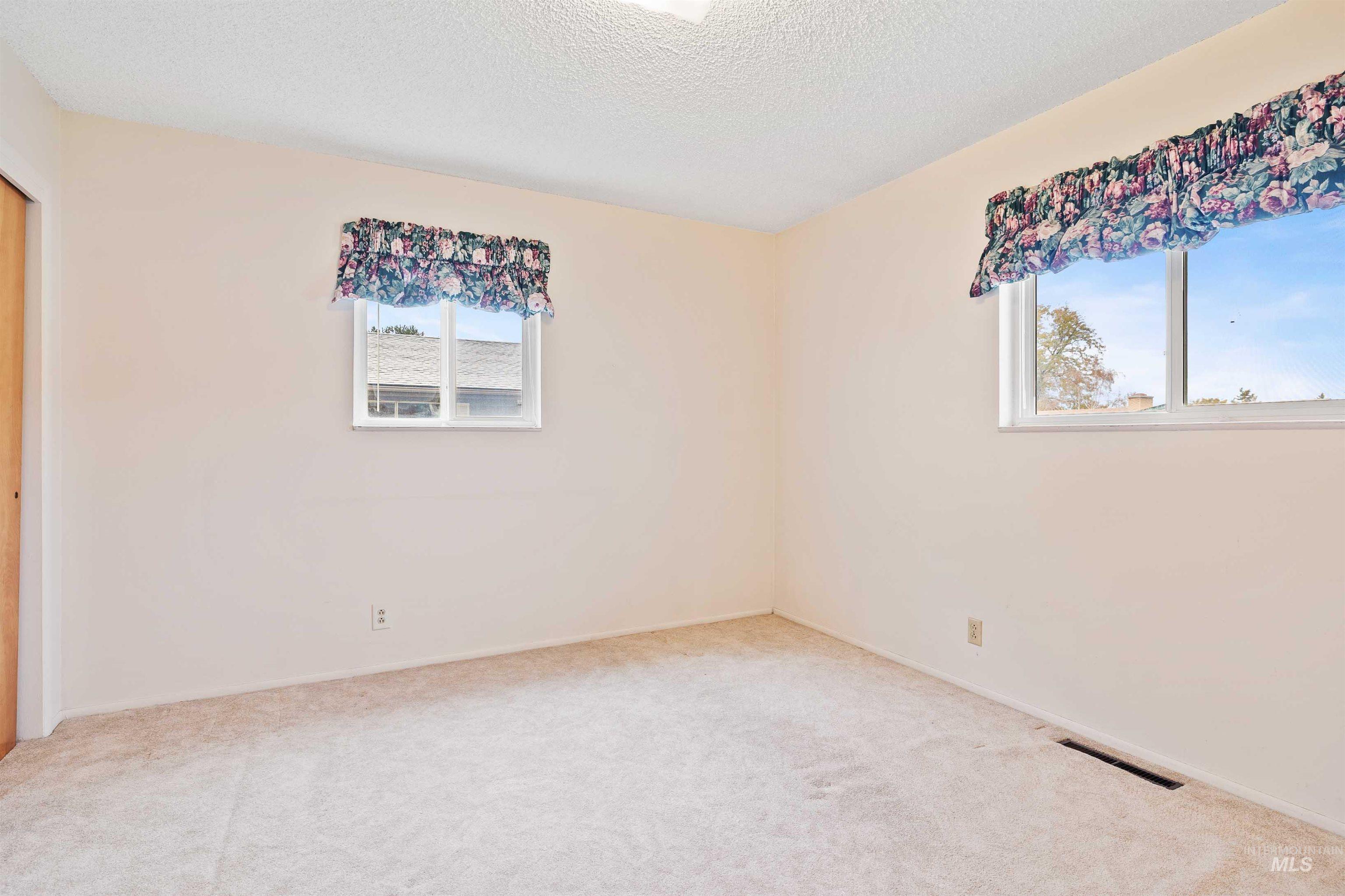 Empty room with healthy amount of natural light, carpet flooring, and a textured ceiling