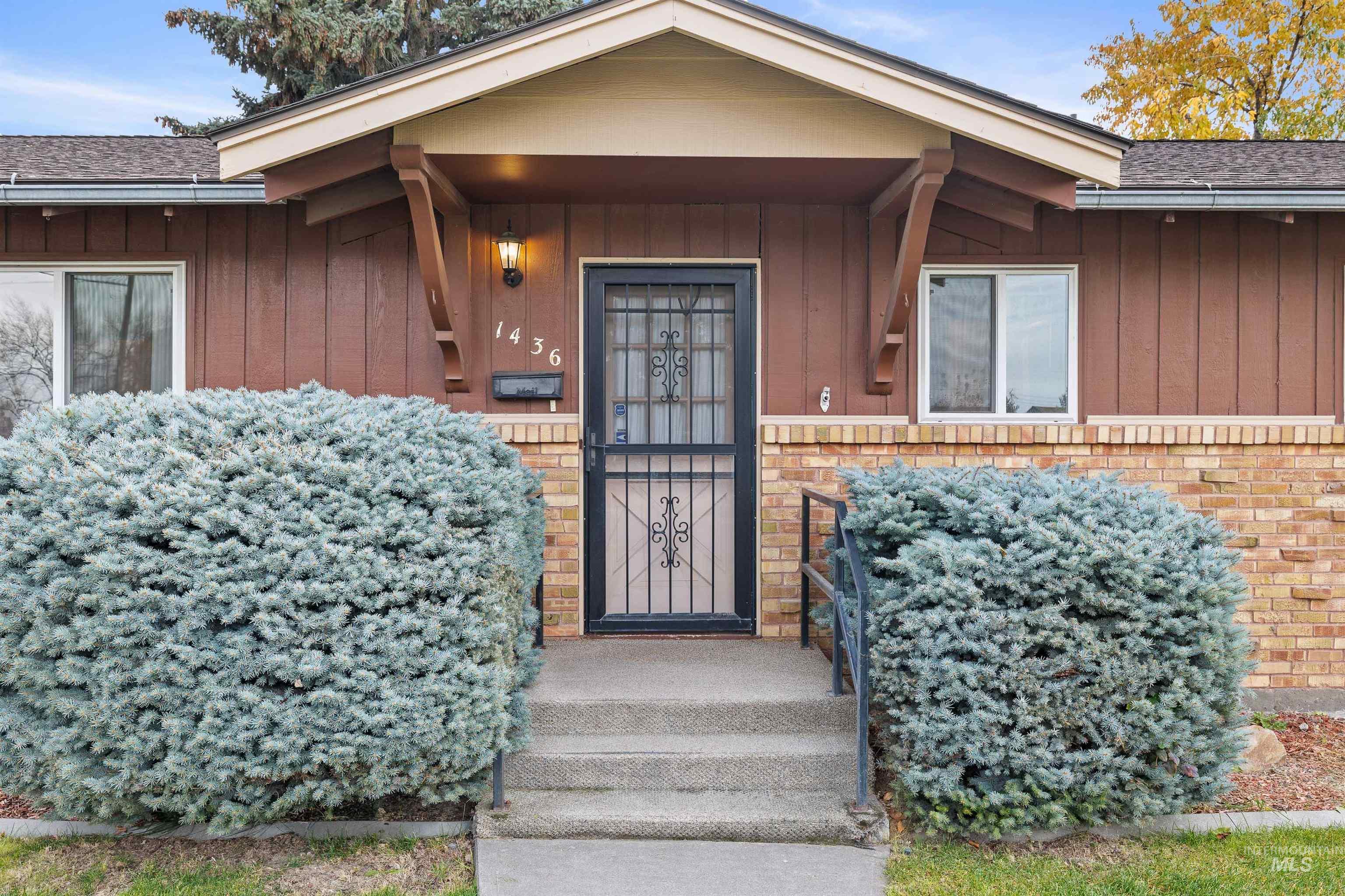 Entrance to property with board and batten siding, brick siding, and a shingled roof
