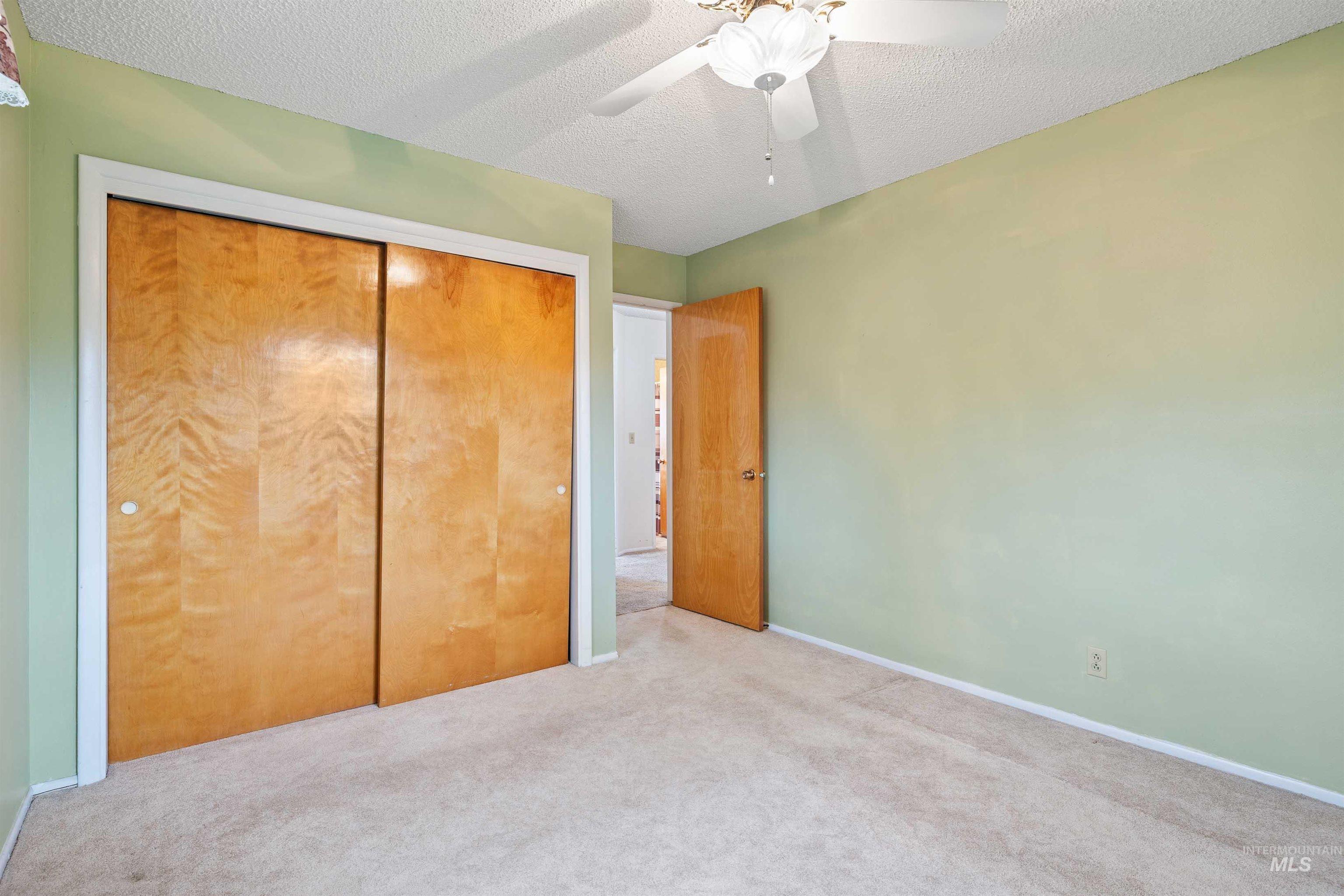 Unfurnished bedroom with a textured ceiling, carpet flooring, ceiling fan, and a closet