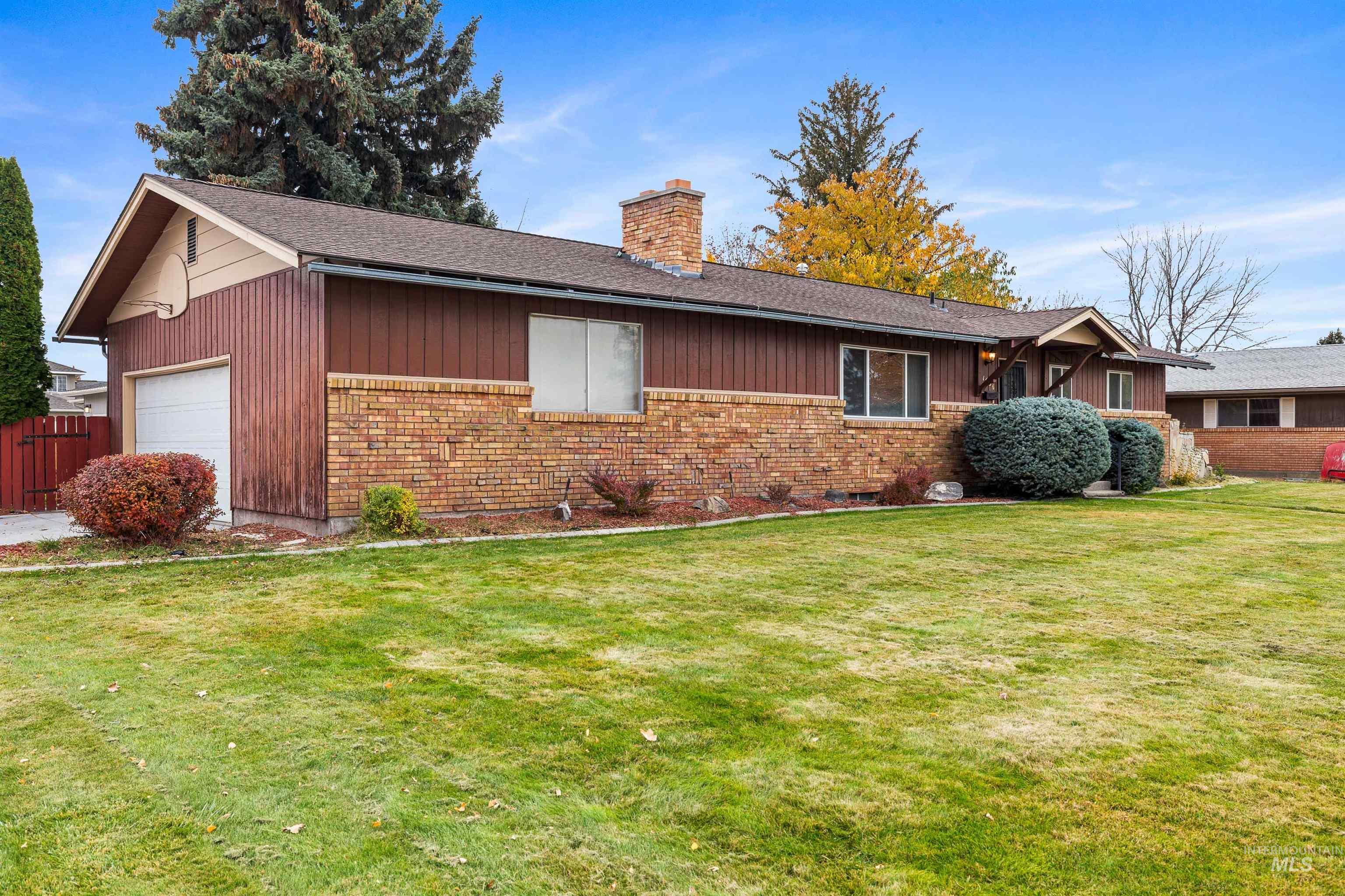 View of front of property with brick siding, a front lawn, a chimney, and a shingled roof