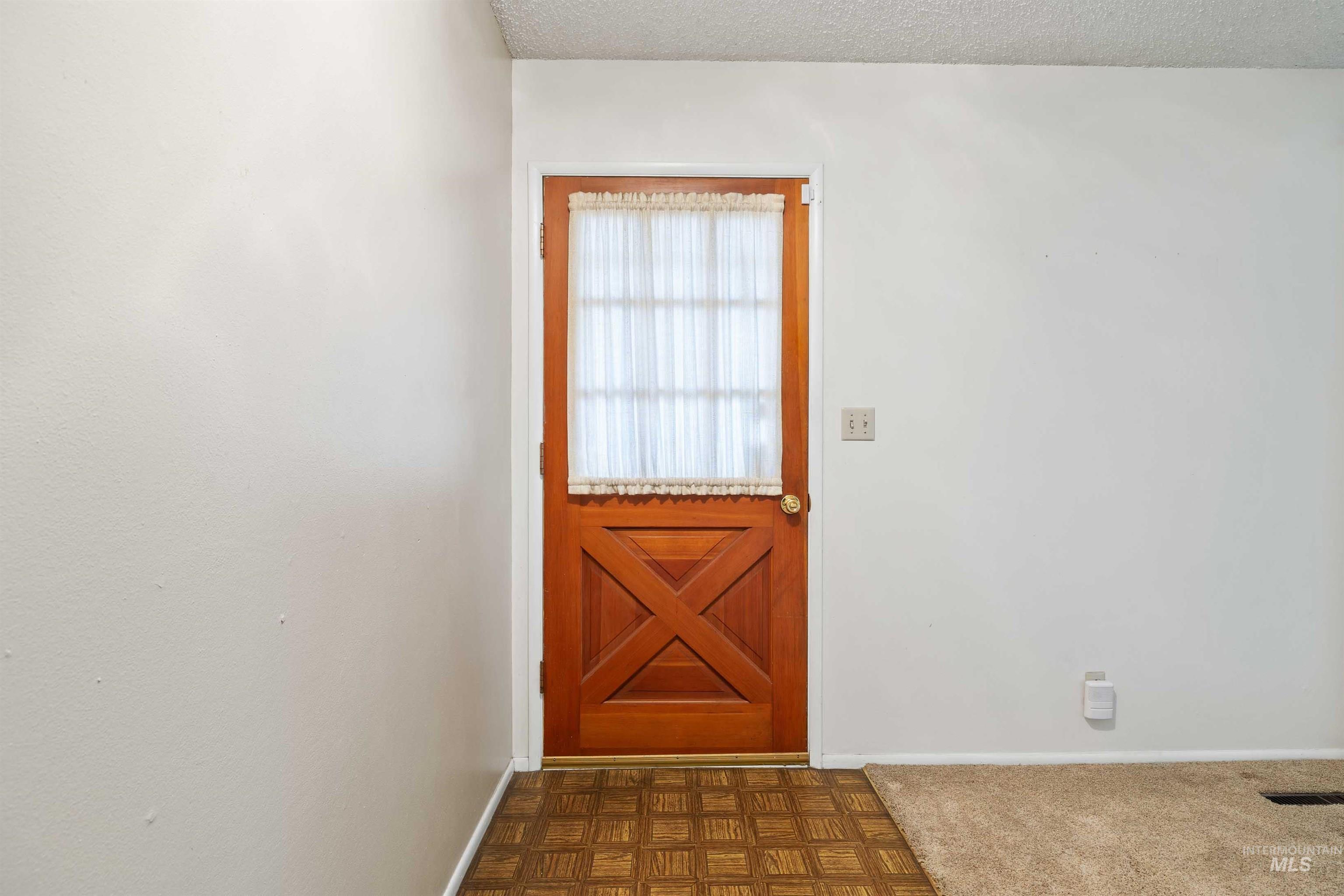 Doorway to outside with a textured ceiling and baseboards