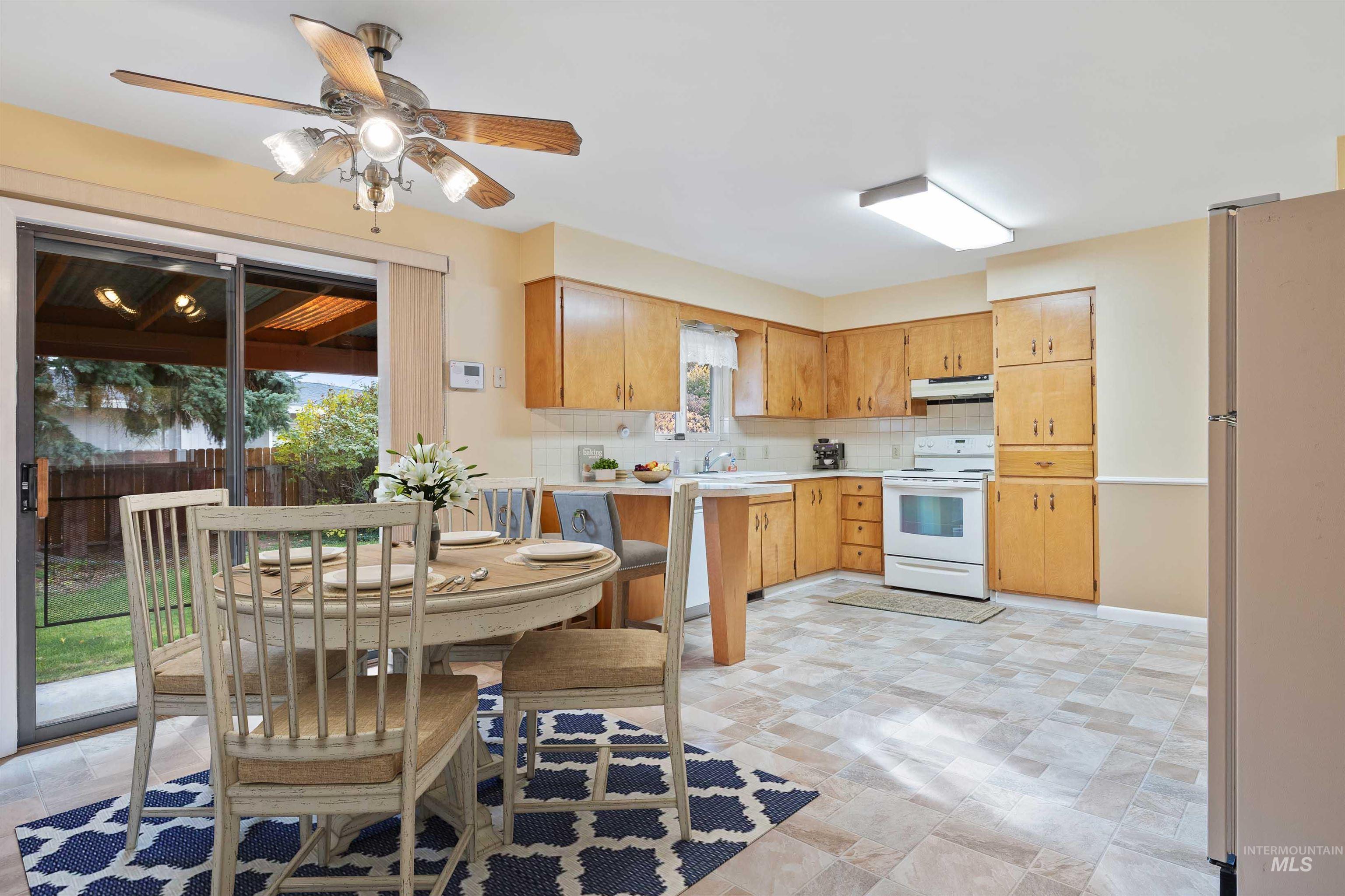 Kitchen featuring light countertops, white appliances, backsplash, under cabinet range hood, and a ceiling fan