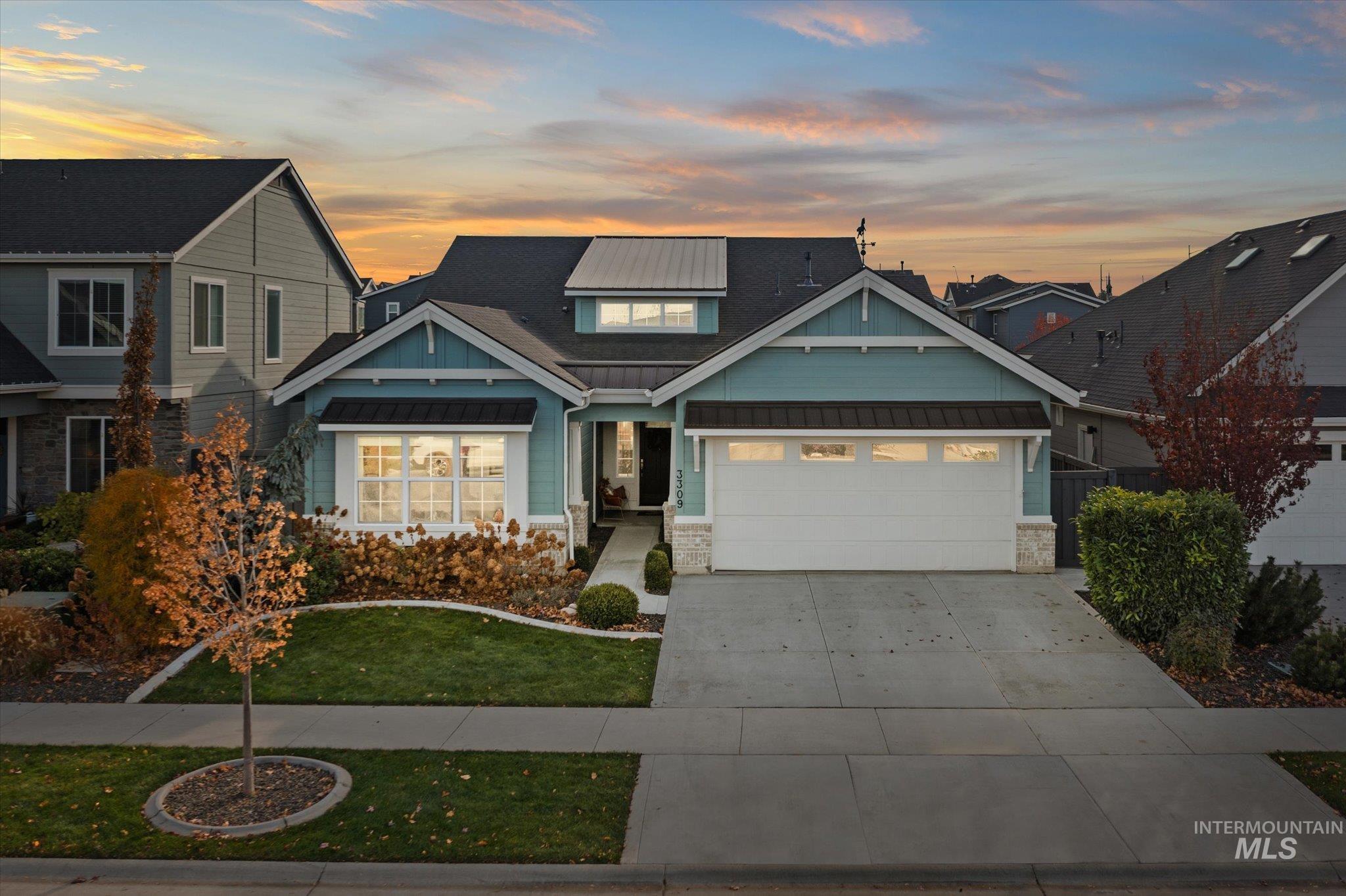 View of front of property with a standing seam roof, a metal roof, a yard, driveway, and a garage