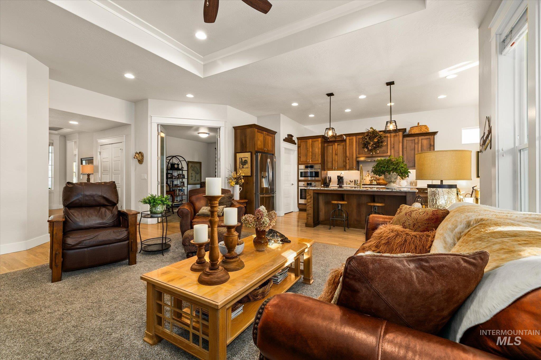 Living area featuring a tray ceiling, ceiling fan, recessed lighting, and light wood-type flooring