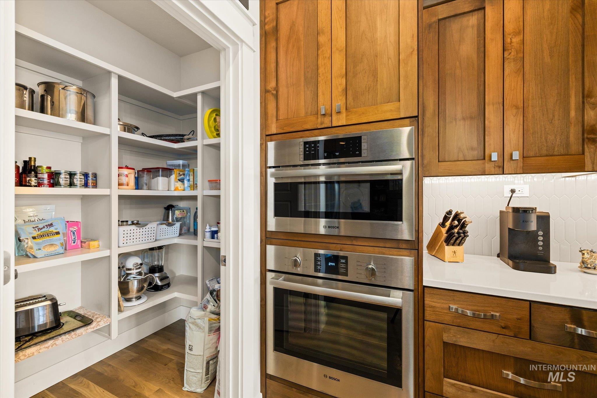 Kitchen with brown cabinets, wood finished floors, and decorative backsplash