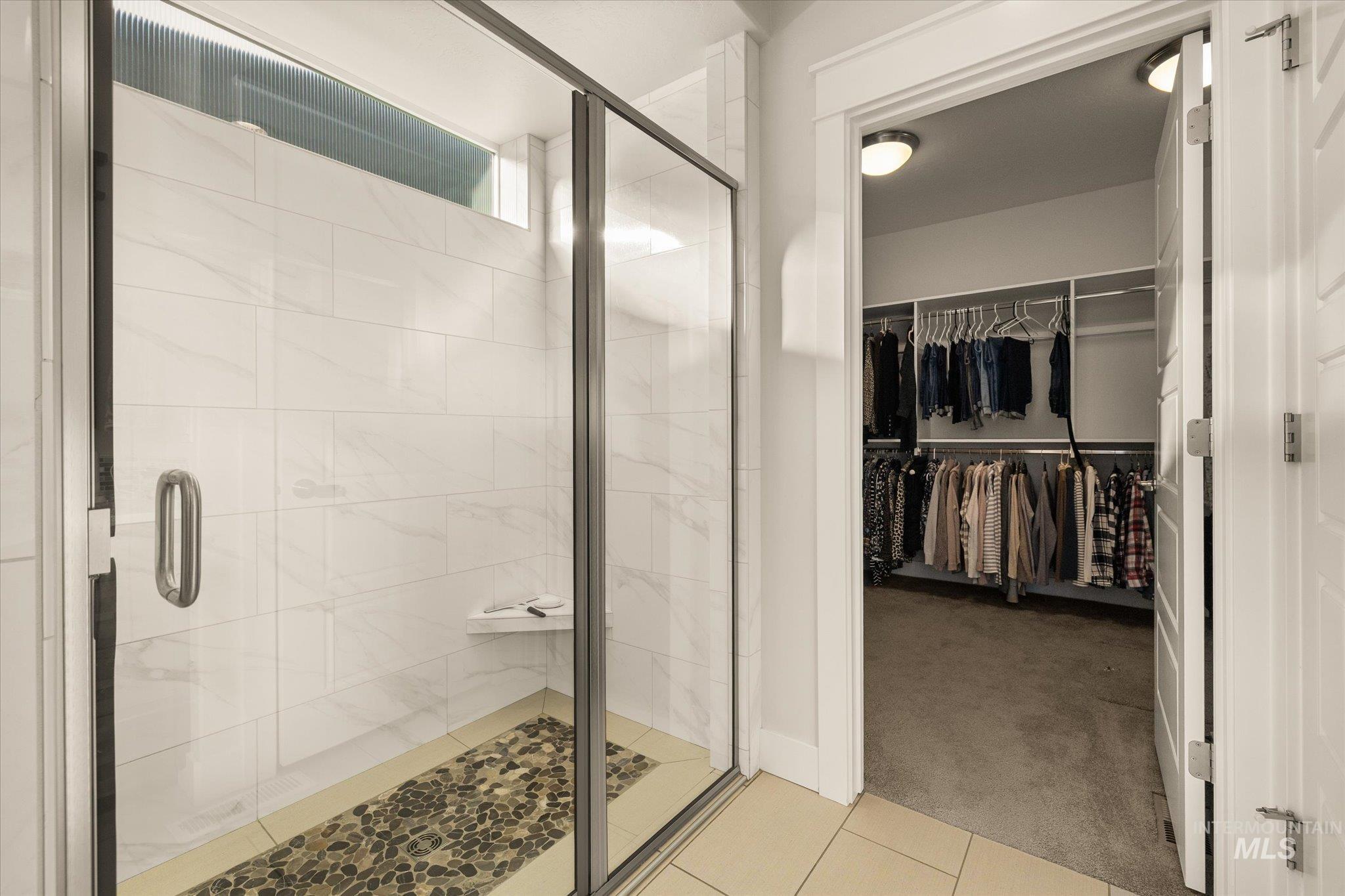Bathroom featuring light carpet, a stall shower, a spacious closet, and light tile patterned flooring