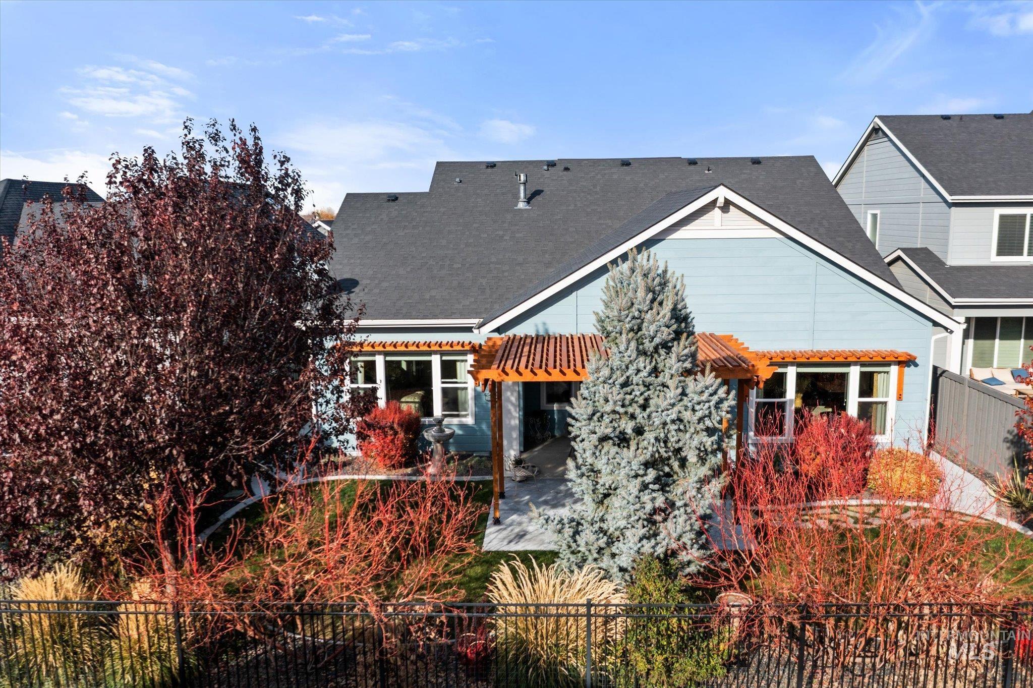 Back of property featuring a fenced front yard, a pergola, roof with shingles, and a patio