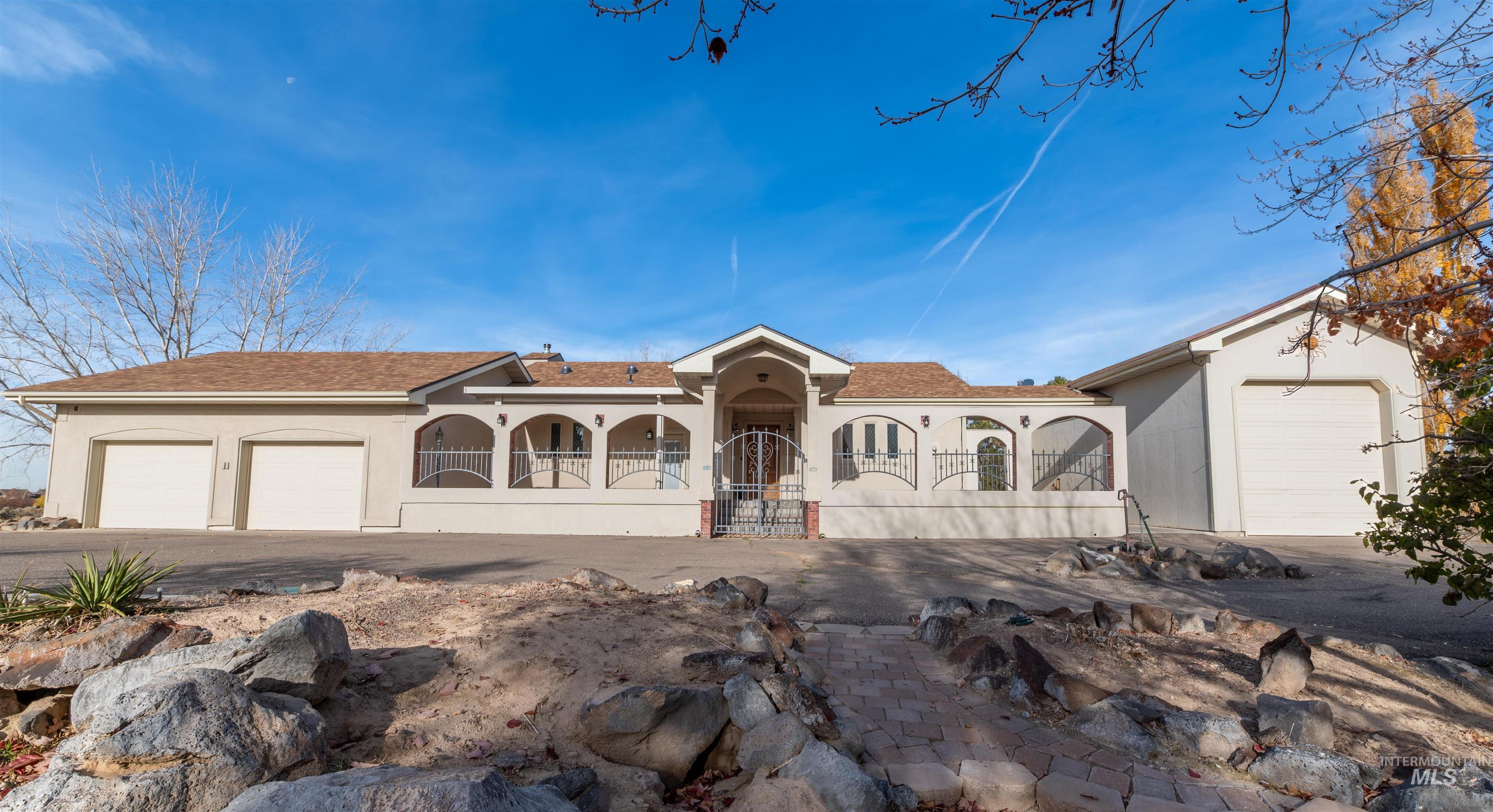 Mediterranean / spanish home featuring stucco siding, a garage, asphalt driveway, and roof with shingles