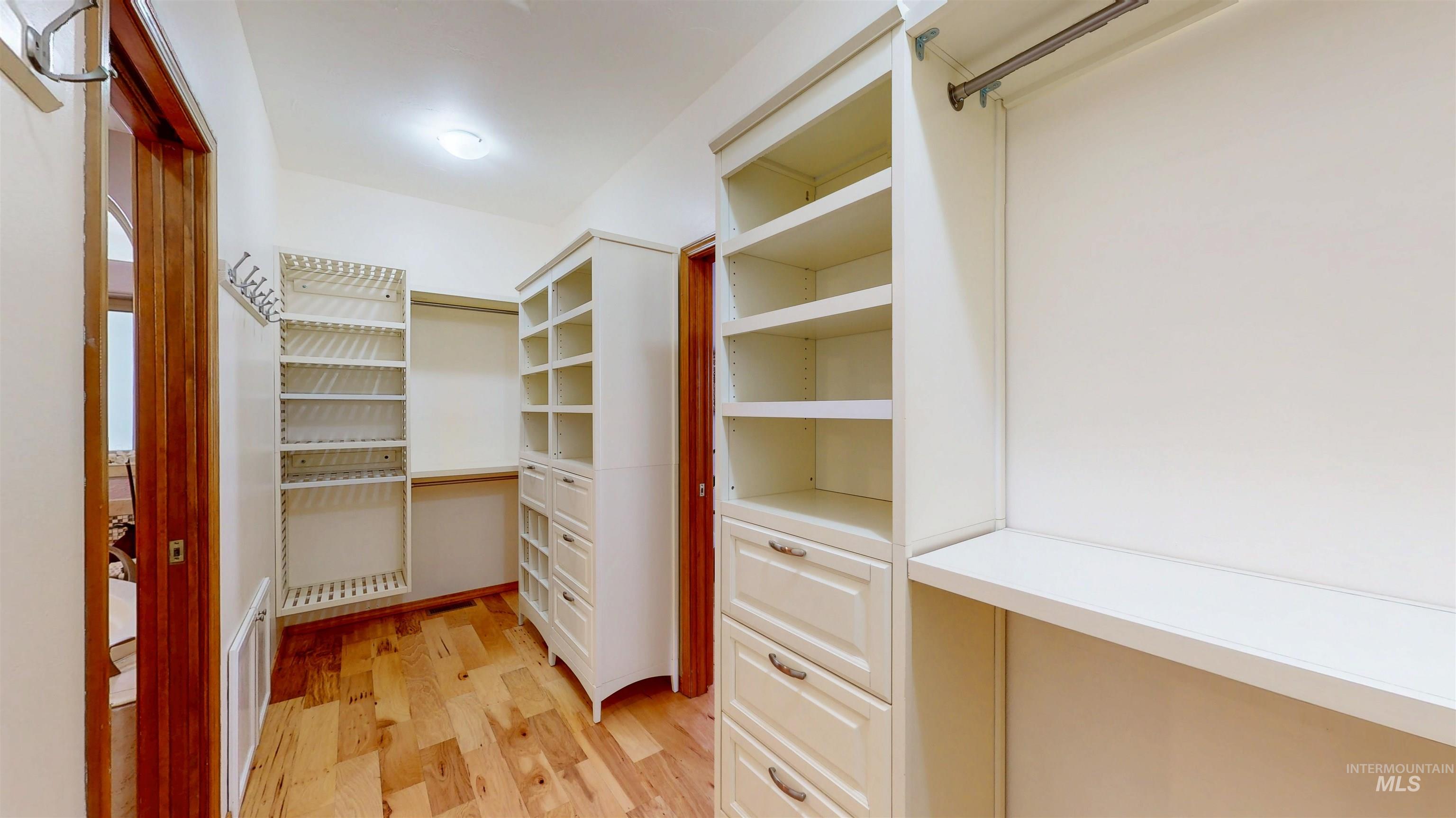 Spacious closet with light wood flooring