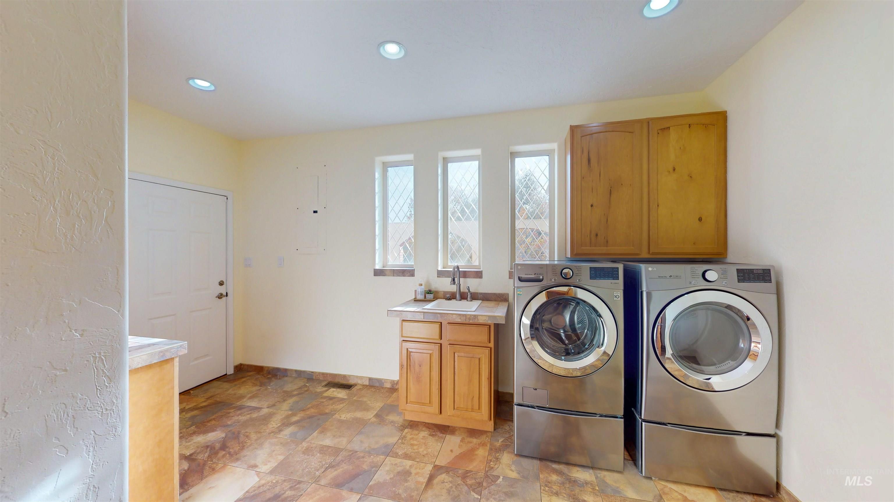 Washroom featuring recessed lighting, stone finish floors, separate washer and dryer, and cabinet space