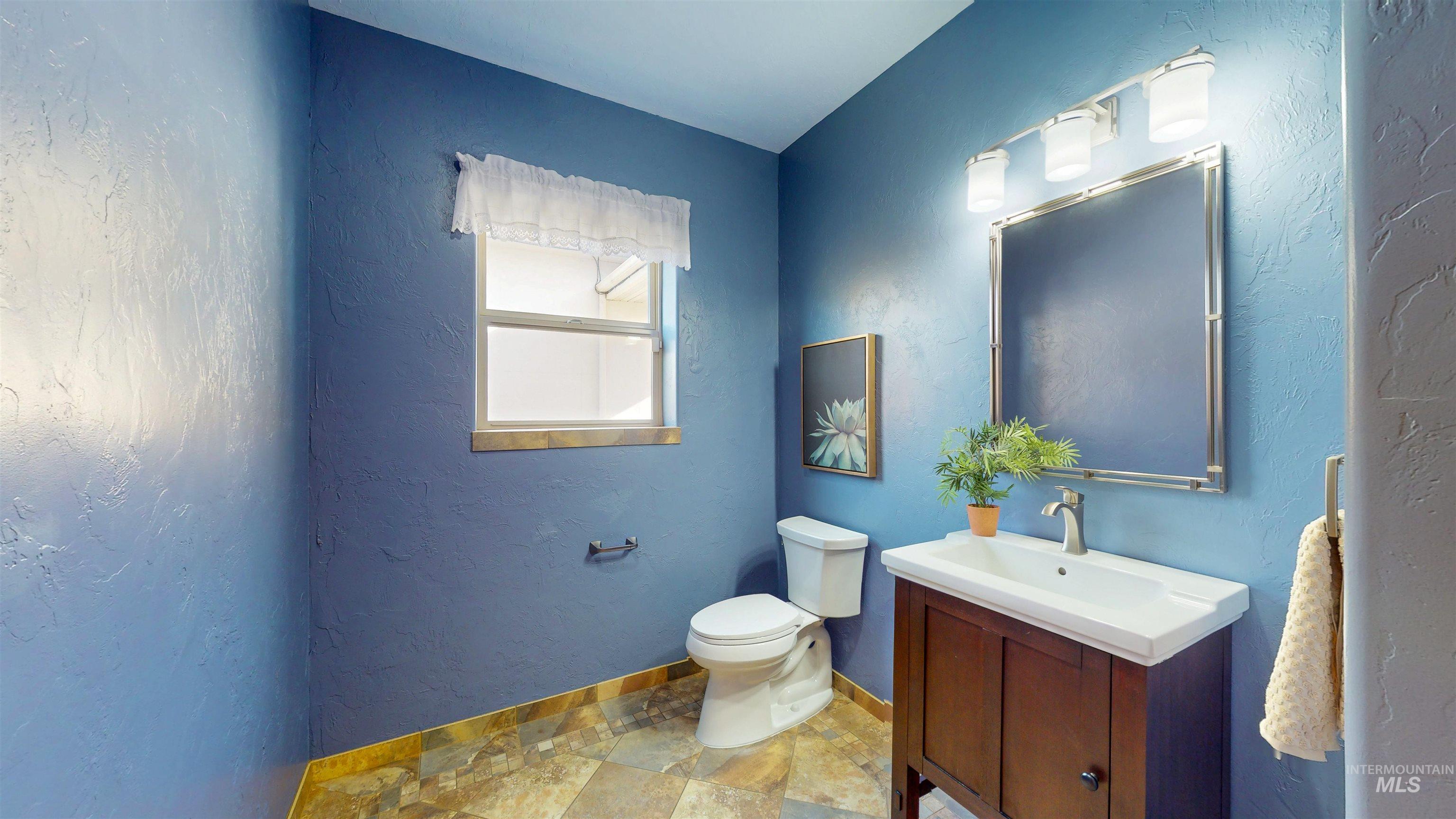 Bathroom featuring a textured wall, vanity, and light stone finish flooring