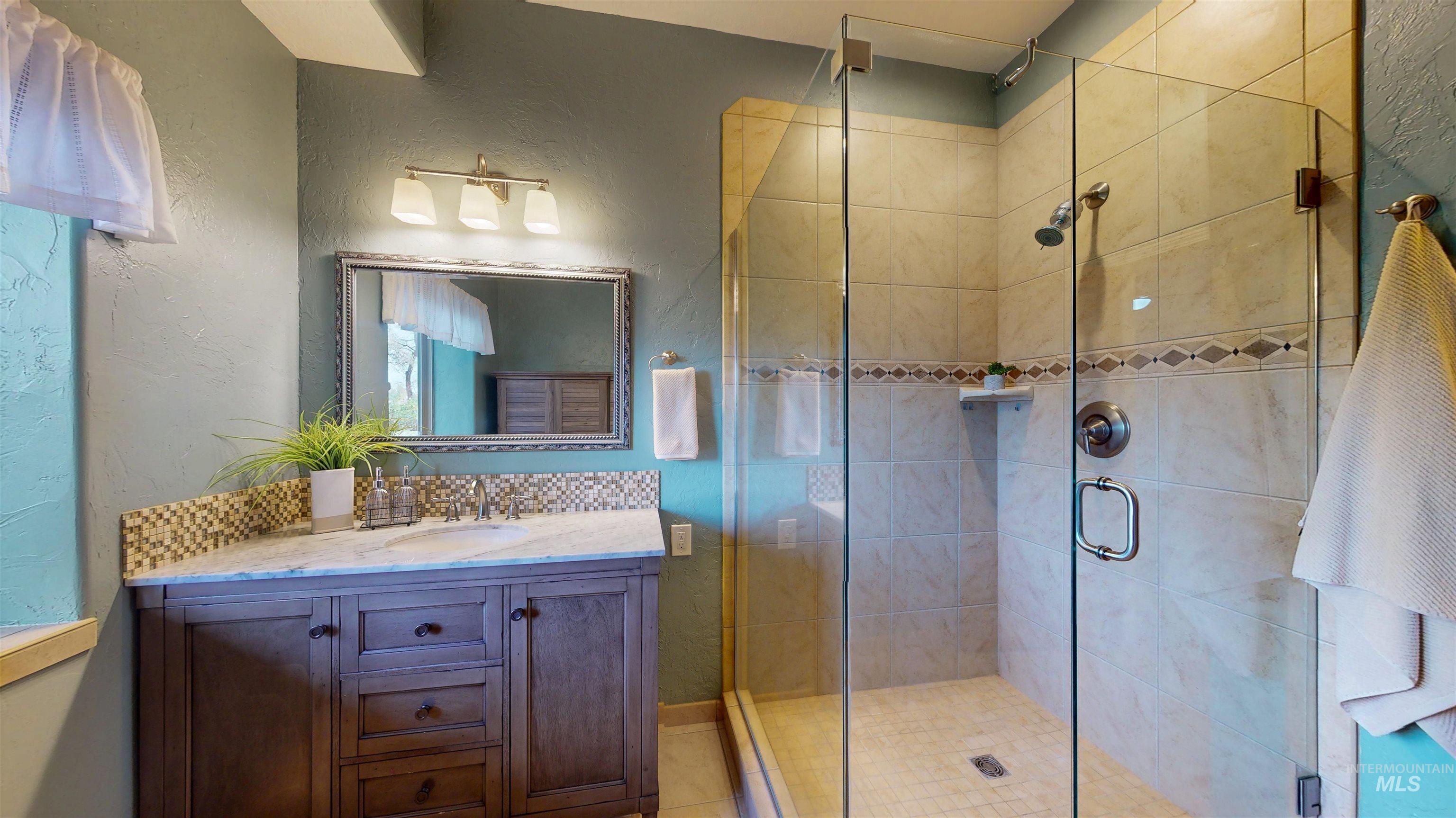 Full bathroom with a textured wall, vanity, and a stall shower