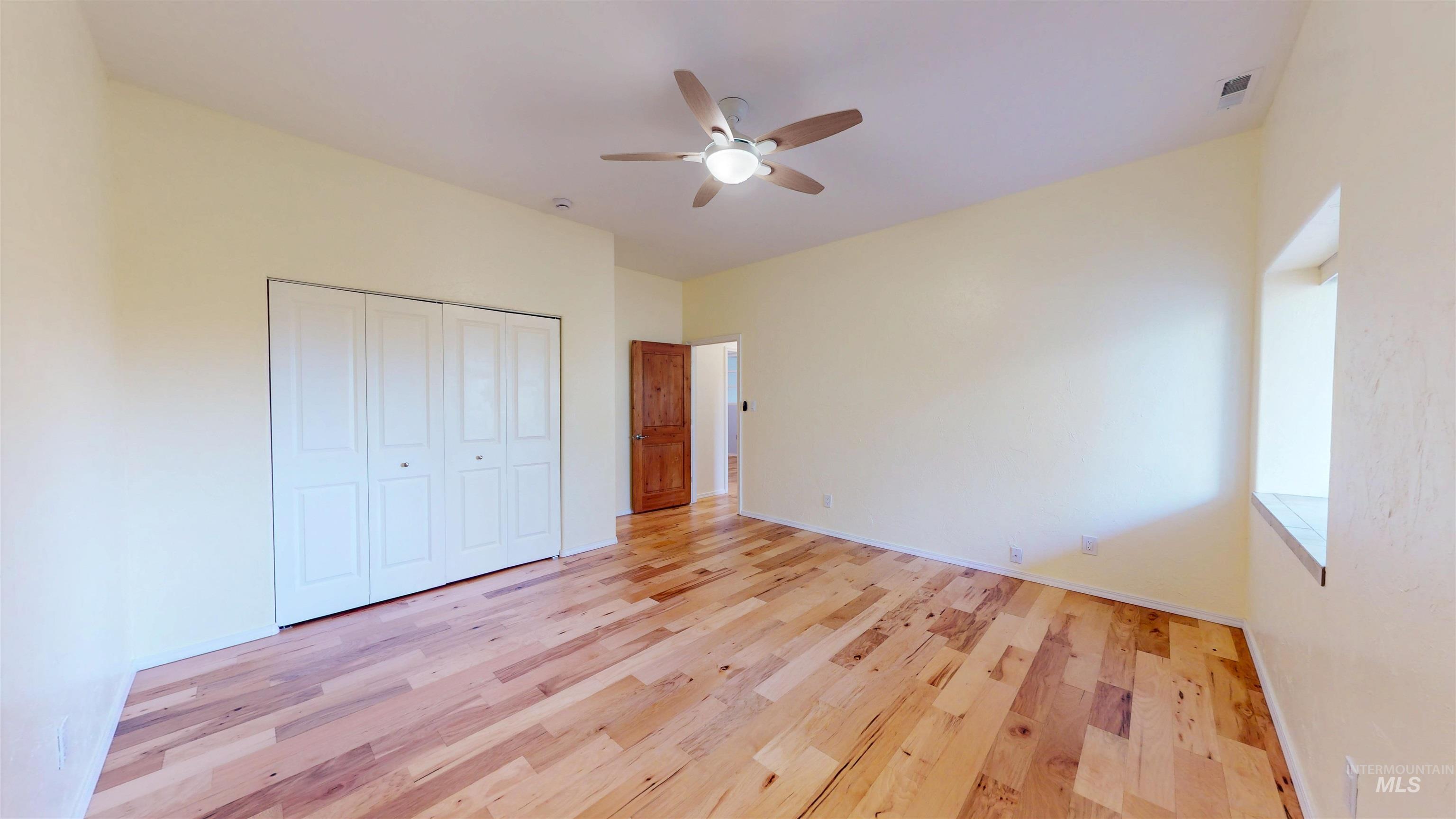 Bedroom featuring light wood flooring, a ceiling fan, and a closet
